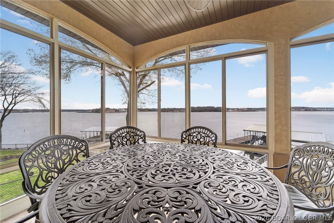 Experience unmatched lakefront living in this extraordinary retreat featuring breathtaking 360-degree views and rare, no-step access to the water. The gentle, walkable lot leads effortlessly to the shoreline, offering expansive main channel views in every direction.  A massive 2-well concrete dock is built for fun and function, complete with a breakwater, swim platform, slide, diving platform, with wet steps for easy water entry—perfect for enjoying true lake life. Inside, panoramic views fill nearly every room, including three ensuite bedrooms and multiple living spaces. With 5 bedrooms total—plus a spacious loft with twin/full bunks—there’s room for everyone. Sold turnkey with upscale furnishings and premium appliances, it’s ready to enjoy immediately. The walk-out lower level features a full second kitchen and bar, ideal for entertaining. Outdoor spaces include a screened deck and large patio overlooking a fenced yard. No HOA and located at the 19 MM off Hwy MM, just minutes from top dining, shopping, and entertainment. A rare opportunity to own a premier lakefront escape with unforgettable views and effortless access.