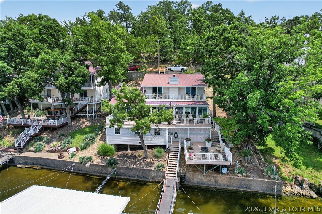 Wake up to BREAKTAKING main channel views from this beautifully updated waterfront retreat offering 77' of shoreline, a 3-well dock, & the Lake of the Ozarks lifestyle you've been dreaming of. This 3-bedroom, 3.5-bath home offers over 3000 sq. ft. with 2 private ensuite bedrooms with walk in tile showers, Walk-in Cedar lined closet, an open floor plan, expansive windows, beautiful main-level flooring, & a STUNNING double-sided stone fireplace that anchors the living space. The stylish kitchen features composite countertops, double ovens, and is designed for entertaining. Step outside to three levels of composite decking, creating multiple spaces to relax and take in the incredible views. Enjoy a gentle walk to the water, an expansive workshop & abundant storage.  Private well & septic along with a Generac generator for added peace of mind. Furnishings are included, making this an exceptional turnkey opportunity, while the boat and personal watercraft are available separately. Whether you're searching for a full-time residence or the perfect lake getaway, this home delivers the waterfront lifestyle buyers come to Lake of the Ozarks to find.