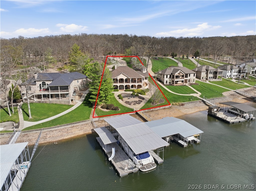 Luxury lake living in prestigious Porto Cima.  This exceptional 6-bedroom home and 4.5 bathrooms offers over 4,500 square feet of beautifully designed living space, perfectly positioned on 133 feet of lakefront. Designed for both comfort and entertaining, the home features a sprawling open floor plan, main-level living. Two full kitchens provide added convenience, ideal for hosting guests.  Step outside to take in breathtaking lake views from two expansive deck areas, complete with a custom BBQ station. The professionally landscaped grounds lead to a gentle walk to the water, where you'll find a 4-well dock with PWC lifts.  This gorgeous home comes completely turnkey including two boats and PWCs. Lake life starts here!