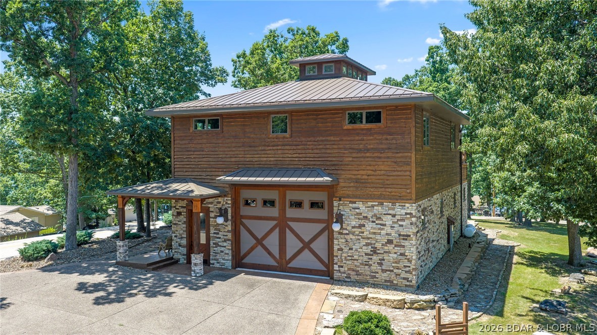 Welcome to a truly extraordinary, custom-built Saltbox architectural masterpiece in Lake Ozark. Nestled in a league of its own, this unique home offers an incredible panoramic water view that transforms every ordinary day into something breathtaking. Built with modern efficiency in mind, the property features a highly efficient geothermal heating and cooling system, two private wells, and a gas fireplace, ensuring year-round comfort with a significantly reduced carbon footprint. For the ultimate hobbyist, a dream climate-controlled garage awaits—complete with radiant heated floors, commercial-grade openers, and two massive 14x16 foot doors designed for a seamless drive-through experience. Inside, the home boasts two large, airy bedrooms and 2.5 beautifully appointed bathrooms. The gourmet kitchen shines with premium quartz countertops and high-end KitchenAid appliances. Step outside onto the expansive concrete deck, the perfect spot to enjoy your morning coffee over shimmering waters or host friends for a showcase sunset. Priced exactly at its recently appraised value, this home has too many upgrades to list. You truly have to see this one-of-a-kind design for yourself.