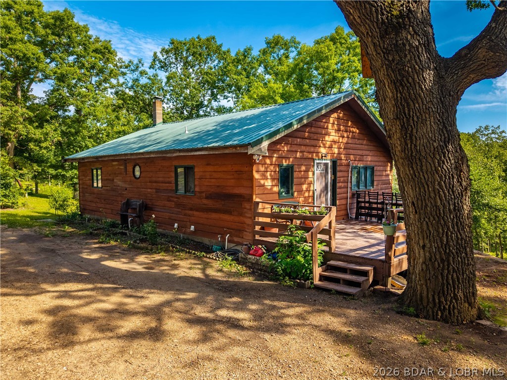 Escape to your own private retreat at 27405 Twin Ridge Rd in Gravois Mills! Nestled on 18 peaceful acres, this charming 3 bed, 2 bath home offers privacy, abundant wildlife, and a true country lifestyle—just minutes from town. The main living room features beautiful shiplap ceilings with open beams, creating a warm and rustic feel. Step outside to enjoy a large deck overlooking your land, perfect for relaxing or entertaining. The walk-out basement includes a lower-level garage for added convenience. Bring your homesteading dreams to life with a fenced garden, chicken coops, and an additional outbuilding. A bonus structure on the property—currently used as an office—could easily become a garden shed, guest space, or small apartment. This is the ideal setting for those craving space, nature, and a little bit of everything. Don't miss this unique opportunity!