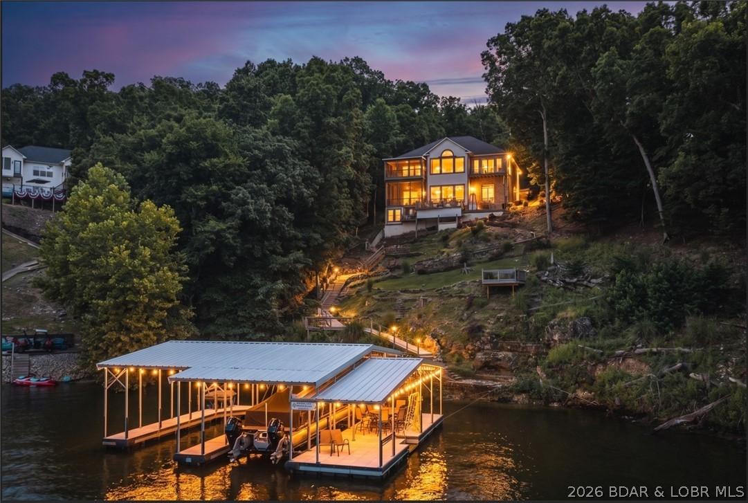 Welcome to refined luxury living in the prestigious Porto Cima Community! This beautifully updated 4-bedroom, 3 full and 2 half bath home offers over 4,656 sq ft of thoughtfully designed living space overlooking the 14-mile marker of the Lake of the Ozarks. The main level welcomes you with soaring ceilings, engineered hardwood flooring, and floor-to-ceiling windows that frame breathtaking views. The spacious primary suite features double closets, jet tub, walk-in shower & stunning views of the lake. The chef's kitchen is appointed with Custom Cherry Cabinetry, Quartz Countertops, Stainless Steel Appliances and both formal & casual dining areas. The lower level is built for entertaining with a 2nd living area, wet bar, full kitchen, media room and plenty of space for your friends and family. Outside you'll find a gentle circle driveway leading to your two car garage and on the lakeside, you'll find spacious decks and screened in porches to enjoy morning coffee or evening cocktails. A cart path leads down to 2 Martini Decks and your 2-Well Ozark Barge Dock with an attached Swim Platform. Enjoy the best of Porto Cima with access to top tier amenities. Schedule your private tour today!