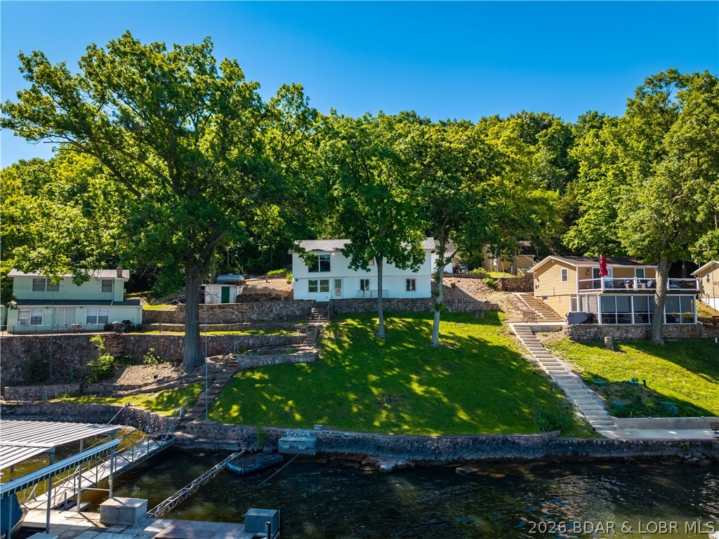 Tucked away on the sought-after Little Niangua Arm, this 3 bed, 1.5 bath lakefront home is all about enjoying everything people love about Lake of the Ozarks. With over 100 feet of gentle lakefront, deep water, incredible views, and calmer waters perfect for swimming, floating, and relaxing, this property checks the boxes that are getting harder and harder to find. The home features kitchens on both levels, offering flexibility for entertaining guests, hosting family, or creating the ideal setup for long lake weekends. A large living room with a fireplace creates the perfect gathering space after a day on the water, while the detached garage and plentiful parking make it easy to accommodate friends and family. Outside is where this property really shines — plenty of room for bonfire nights, cornhole tournaments, and soaking in the lake views while watching the boats pass by. Inside, this home is ready for you to make it your own and create the perfect lake getaway, full-time residence, or investment opportunity. Great shoreline, incredible views, and endless potential — this is the kind of lake property people hold for generations. Deep water 14' in front & 25' at the rear of dock.