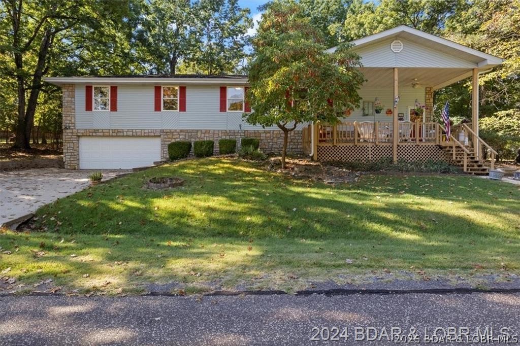 Four connected lots, nearly 2,900 square feet, three full baths, a whole house generator, and a 2-car attached garage with workshop in the Camdenton School District just north of town on Highway 5 at $309,000. That is a combination that is genuinely hard to argue with in the Lake of the Ozarks area. Located in Camelot Estates in Camdenton, Missouri, this 3-bedroom 3-bath raised ranch sits in an established neighborhood with a mix of waterfront and off water homes, subdivision boat ramp access, two community pools, tennis courts, and playgrounds. The layout is designed for real living with multiple gathering spaces, a centrally located kitchen beside the dining area, a lower level family room with a wood burning fireplace, and a sunroom that stays bright year round. The large covered front deck looks out over four connected wooded lots that give you privacy and room to breathe. Camdenton is the county hub for Camden County with shopping, dining, medical care, the aquatic center, and city park all close by, and Lake Valley Golf and Old Kinderhook are both in the area for buyers who want the full Lake of the Ozarks lifestyle without the waterfront price tag.