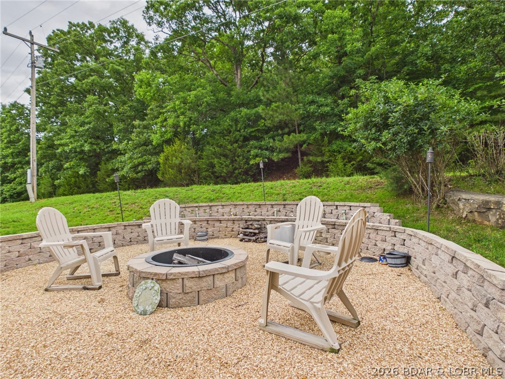 This unique property offers privacy, recreation, and endless potential. Included is the home plus an additional second-tier 0.6-acre lot above the house featuring seasonal lake views, a level building site, and no restrictions—perfect for future expansion. Enjoy morning coffee and evening sunsets from the spacious deck overlooking the lake and wooded surroundings. A private off-road trail adds even more adventure, making this property ideal for ATV enthusiasts and nature lovers alike.The 1,224 sq ft home features an open floor plan with vaulted wood-beam ceilings, warm wood accents, an updated kitchen with stainless steel appliances, 2 bedrooms, a bonus room, and 2 bathrooms. Outside, a firepit and gathering area create the perfect setting for entertaining. The 1,040 sq ft oversized garage/shop offers ample room for vehicles, boats, and toys, plus an attached bedroom and full bath—ideal for guests, a workshop, or rental income potential. Additional features include patio doors with built-in blinds, Levolor shades, modern tilt windows, and a clean, lighted crawl space with standing room in portions. A rare opportunity to own a versatile Lake of the Ozarks retreat with room to grow.