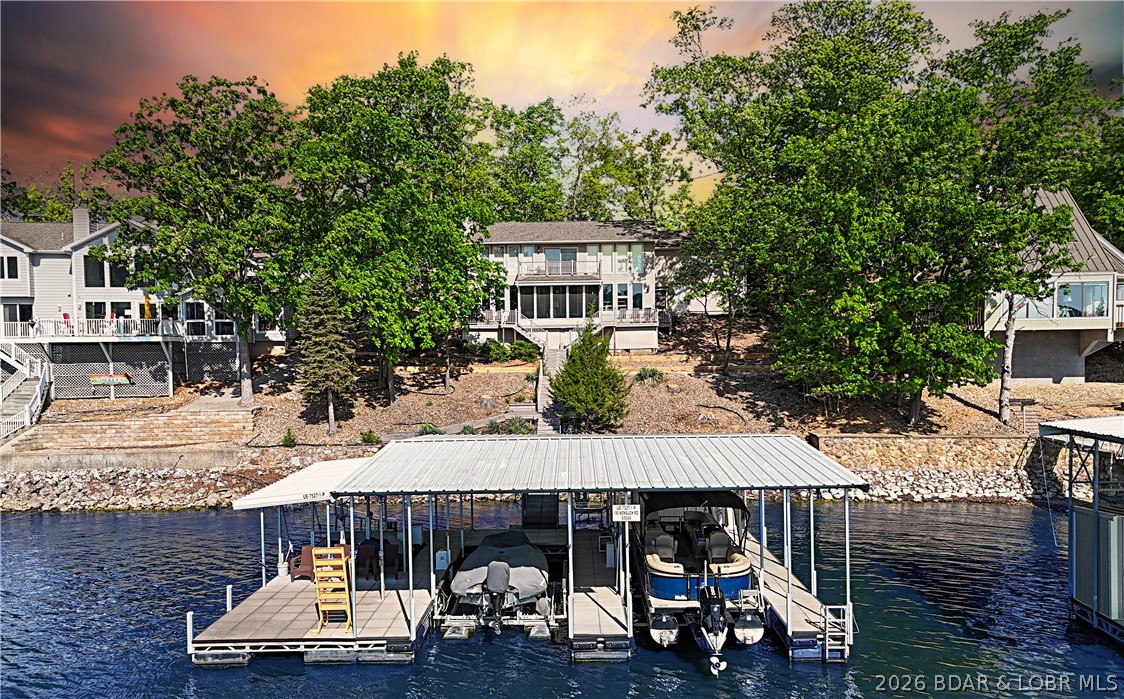 This 3-bedroom, 2-bath home on Nonsuch in Lake Ozark is now available for the first time in many years. The unique upper level is a dedicated primary suite featuring a living area with a stone gas fireplace, a private kitchen, a walk-in closet, a beautiful, updated bath, and a bonus room or office with a built-in Murphy bed and garage access. The main level includes a second gas fireplace, two bedrooms, a bathroom, and a fully updated custom kitchen with granite counters and a walk-in pantry and LVP flooring. Let's head to the dock through the screened porch an out to the no-maintenance decking. At the dock you'll find the covered double PWC lift, two 12 x 28 slips, a storage shed, a fish cleaning station, and a swim platform with wet steps. Enjoy the great view of the main channel and some cove protection. Not in Four Seasons so very rentable. Make some money while you enjoy this home with friends and family. I think you'll want to spend your lake days here or just move here full time. Nonsuch is a cul-de-sac so not much traffic here. See it soon!!!