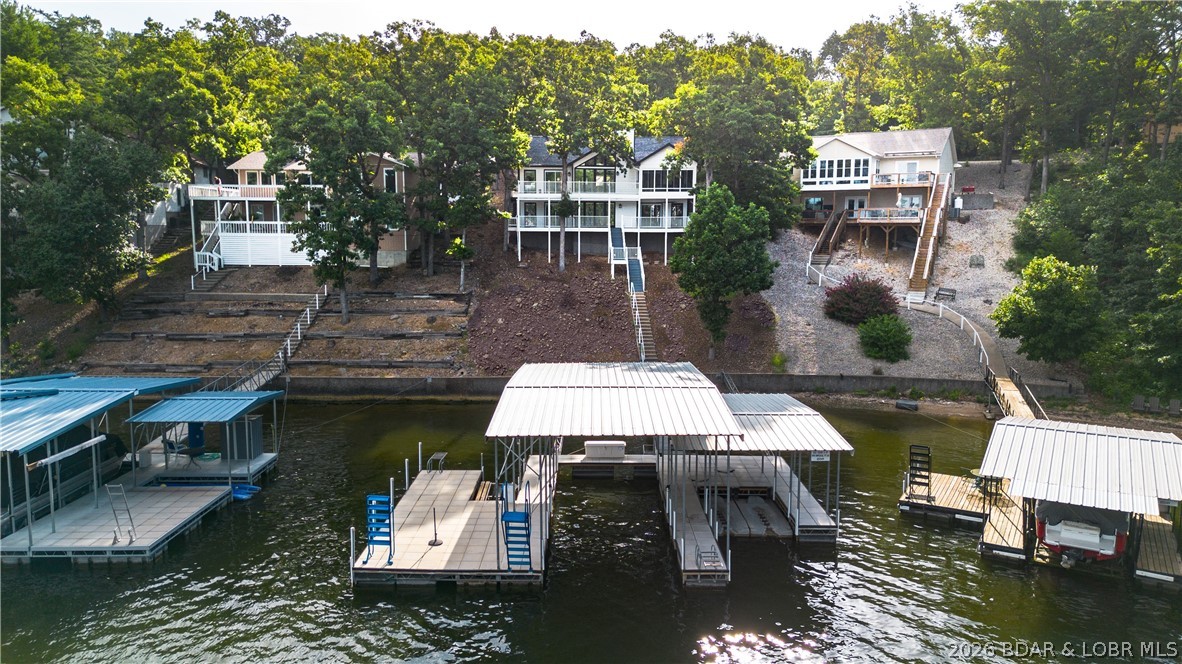 This beautifully remodeled 5-bedroom, 4-bath home in the Village of Four Seasons captures breathtaking main channel views while enjoying the protection of a deep-water cove. With over 3,100 sq ft, multiple living areas & a refreshing coastal-inspired design, there's plenty of room for family/friends to gather. Nearly $170,000 in upgrades completed in 2025 have transformed this home into a true turnkey retreat. The impressive list includes 3 beautifully renovated bathrooms, custom bunk room, quartz countertops, new flooring, fresh interior paint, updated lighting/plumbing fixtures, remote shades, wet bar with quartz tops, added walk-in closets/organizers, new water heater, electronic locks, & more. Spend more time enjoying the lake and less time working on projects. The spacious primary suite features a luxurious bath with soaking tub and walk-in closet, while the climate-controlled sunroom, fireplaces, expansive lakefront decks & multiple gathering spaces make this home ideal for entertaining in every season. Outside, concrete dock offers 2 boat slips, PWC slips, & easy access to great boating! All of this located with use of the amenities the Village of Four Seasons is known for.