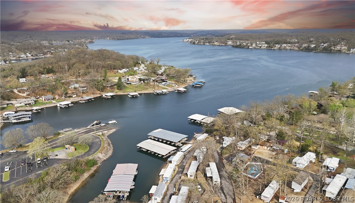 Here is a vacation home steps from the water with a nice view of the cove and main channel for a great price! A 2 bedroom 1 bath mobile home in a great location by water and land.  Located at the 11 MM right across from the Shawnee Bend Public Boat Ramp.  Entertaining to watch!  The owner loves fishing and sitting on the large covered deck looking at the lake and listening to all of the birds in the morning. There is a swim dock, swimming pool and also includes a 9x24 covered boat slip.  No rentals are allowed. Mobile home is on leased land with a monthly assessment. Home has central air and heat and a newer flooring.  Small storage shed on the side and large blacktop parking area next to home. Schedule your showing today and get your lake vacationing started.