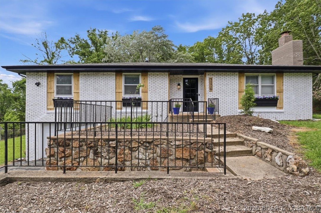 This beautifully updated 3-bedroom, 1.5-bathroom home offers a perfect blend of comfort and style near the Lake of the Ozarks. The exterior boasts a classic painted brick and vinyl finish, charming window planter boxes, and a stone retaining wall. Inside, an inviting open-concept living area features low-maintenance flooring and a painted brick fireplace. The modern kitchen highlights crisp white countertops, stylish gray cabinetry with open shelving, and stainless steel appliances. Step outside to enjoy a refreshing lake view, or relax on the covered patio and fire pit in the backyard . An additional fenced lot with an existing shed provides excellent space for hobby projects, a future workshop, or room to build. Complete with a convenient single-car garage, this property is ready for its next owner. Schedule your tour today!