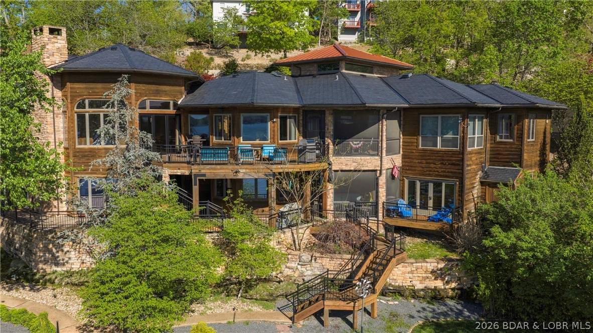 Lodge-style lakefront retreat sitting on over 1 acre with an impressive 276 feet of lakefront. Situated in Four Seasons, this 6 bedroom home features 7 bathrooms with every bedroom designed as a private ensuite. The cove location is the perfect blend of water while still capturing wide-open views, with plenty of room to add a pool if desired. Originally built in 1993 and completely renovated down to the studs in 2009, the home showcases hand-scraped hickory floors, a new DaVinci slate tile roof, and quality finishes throughout. Multiple expansive decks create several entertaining spaces, complemented by a dedicated hot tub room overlooking the lake. Inside also includes an office and private theatre room for added functionality, while the home comes fully furnished, so you can move right in and start enjoying the lake. The large dock features new concrete tiles along with a 15x48 slip, 12x36 slip, and dual PWC slips to accommodate all your lake needs. A 3-car garage and ample additional parking complete the package. This is a rare opportunity to own a true lakefront estate with acreage, extensive lakefrontage, and exceptional amenities.