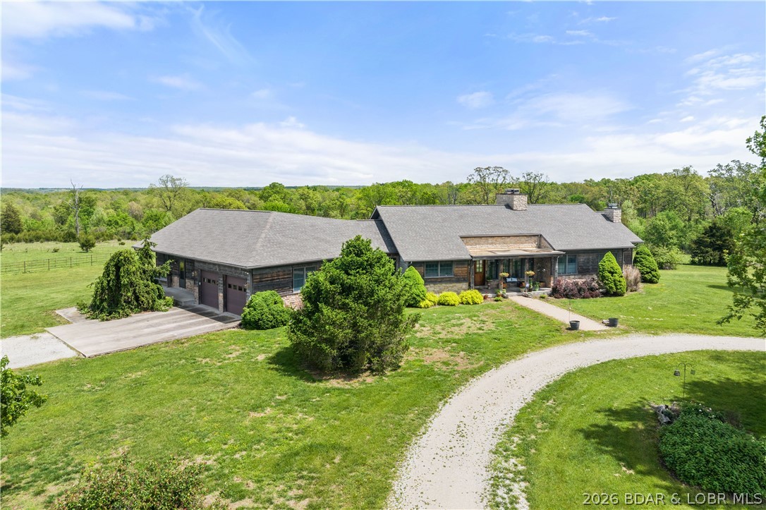 Prepare to be impressed as you pass through brick pillars & down a winding private lane to this unique 120-acre sanctuary. Fenced & currently home to cattle & horses, this stunning working farm features three barns, two ponds, & four livestock watering holes. Nestled within this expansive property is an incomparable custom-built home radiating character & charm. The Great Room invites you in with an open floorplan, soaring vaulted beamed ceilings, & a cozy stone fireplace. The dining area flows seamlessly into a gourmet kitchen, leading to a massive screened-in deck perfect for enjoying breathtaking views. The main level hosts an oversized master suite complete with a fireplace, a spa-like bath with a soaking tub & walk-in shower, plus a private den. Every bedroom is an en-suite! A wonderful guest suite offers a kitchenette, fireplace, & private bath. The lower-level walkout basement adds a large family room & two additional bedroom suites. Bonus: a charming guest house located within the main barn. With wooded acreage teeming with wildlife & eagle nesting spots, this is perfect for homesteading, multi-generational living, or a short-term rental. The possibilities are endless!