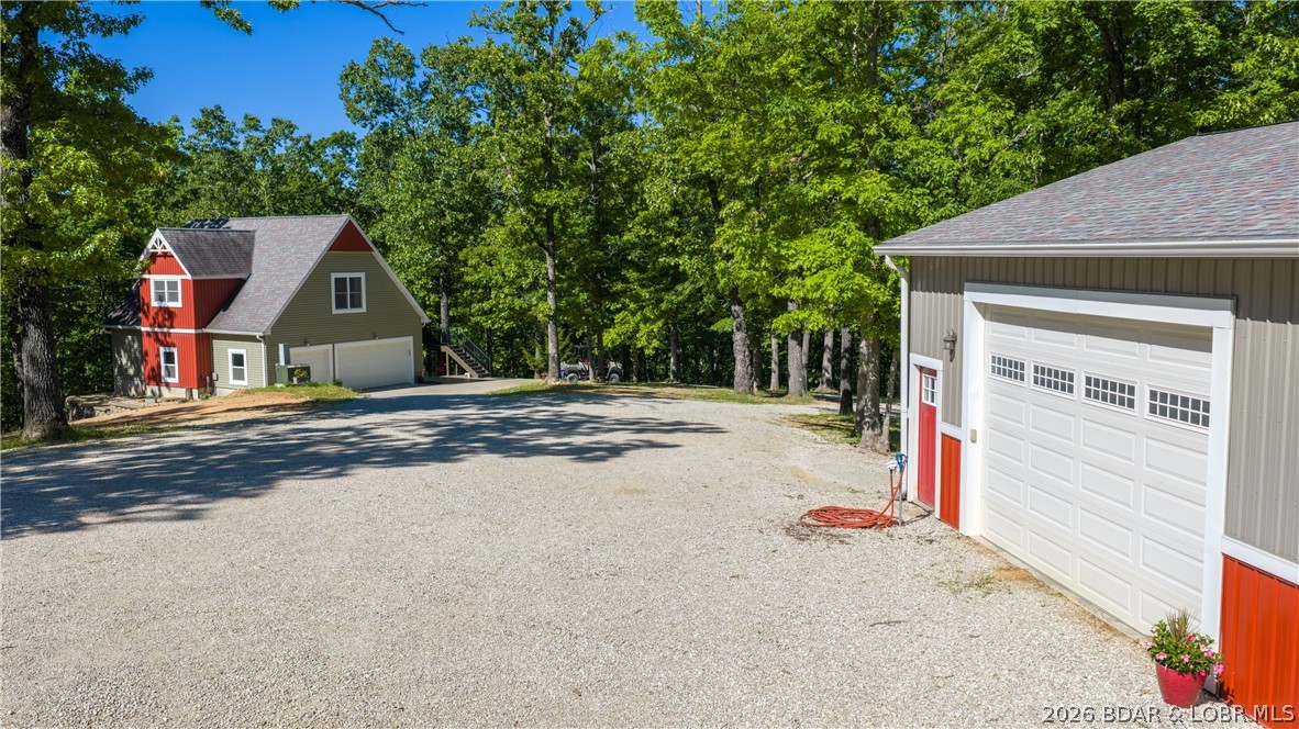 Rare opportunity to own a highly versatile and private 5.5 acre lake property in Camdenton at the 35 mile marker. This unique setup includes a 2 bedroom, 2 bath home positioned above a spacious 3 car garage, surrounded by mature trees with a beautifully cleared area offering exceptional privacy and room to expand, including the potential to build an additional home. Detached from the main home sits a massive 30x40 shop (1200 sf) plus a fully finished 600 sq ft, 1 bedroom, 1 bath apartment built in recent years, featuring modern finishes, full kitchen, washer and dryer, and a loft space, ideal for guests, rental income, or extended family. This property offers true flexibility with multiple living options, perfect for full time living, a second home, or income producing potential. The property also includes a private 2 well dock located just a short golf cart ride away through a wooded trail, tucked in a quiet cove setting with 10x24 and 10x20 slips and room to add a PWC slip. A rare combination of acreage, privacy, shop space, multiple living quarters, and lake access that is hard to find at the Lake of the Ozarks.