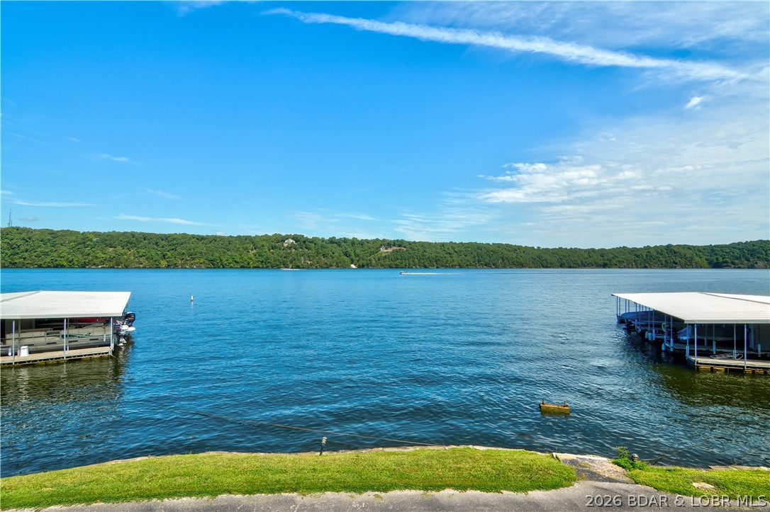 Space, comfort, and value come together in this furnished condo at Osage Heritage located at the 29 Mile Marker of Lake of the Ozarks. With easy parking just steps from the door, getting in & out is incredibly convenient. Inside you’ll find a spacious open floor plan that connects the living, kitchen, and dining areas—perfect for relaxing with family or entertaining guests. One of the standout features is the wraparound deck, offering an expansive outdoor living space with a big lake view from the main part of the deck.  It also includes a gate with direct access to the grassy area, making it easy to enjoy the outdoors.
The huge master suite features an attached bath with walk-in shower, while the generous guest bedroom sits conveniently across from the second full bathroom. The seller has recently installed new flooring & appliances giving the condo a fresh, updated feel that shows well. The unit includes a 12X32 boat slip in a new dock plus access to the community pool just a short walk away. Osage Heritage does not allow nightly rentals, creating a quieter, more relaxed atmosphere. For the size, furnishings, boat slip, and location, this truly is a lot of condo for the money.