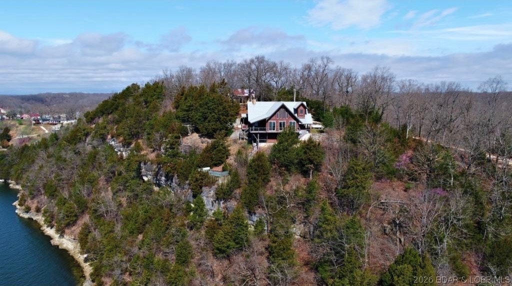 A VIEW FOR MILES!
This one-of-a-kind custom log home showcases stunning craftsmanship, featuring hand-selected Cypress logs sourced from Georgia and rich cherry wood flooring throughout. Soaring ceilings with exposed wood beams and a dramatic wall of windows flood the home with natural light while perfectly framing the breathtaking panoramic lake views. Open-concept floor plan flows seamlessly into a spacious living area, a beautiful stone wood-burning fireplace. Step outside onto expansive decks, complete with a hot tub and a signature martini deck—ideal for relaxing or hosting guests while taking in the scenery. The home offers 2 bedrooms plus an open loft (perfect for a 3rd bedroom or additional living space), along with a large 2-car garage already plumbed for a future bathroom. Additional features include solid wood custom entry doors, iron railings, granite countertops, and a durable composite slate roof with a 50-year warranty. Two gated entrances, the property offers ample parking, and exceptional privacy.
Truly one of a kind. 

*Tenant Occupied. Photo provided prior to tenant occupancy. Adjacent 2.3 acres being sold separately.