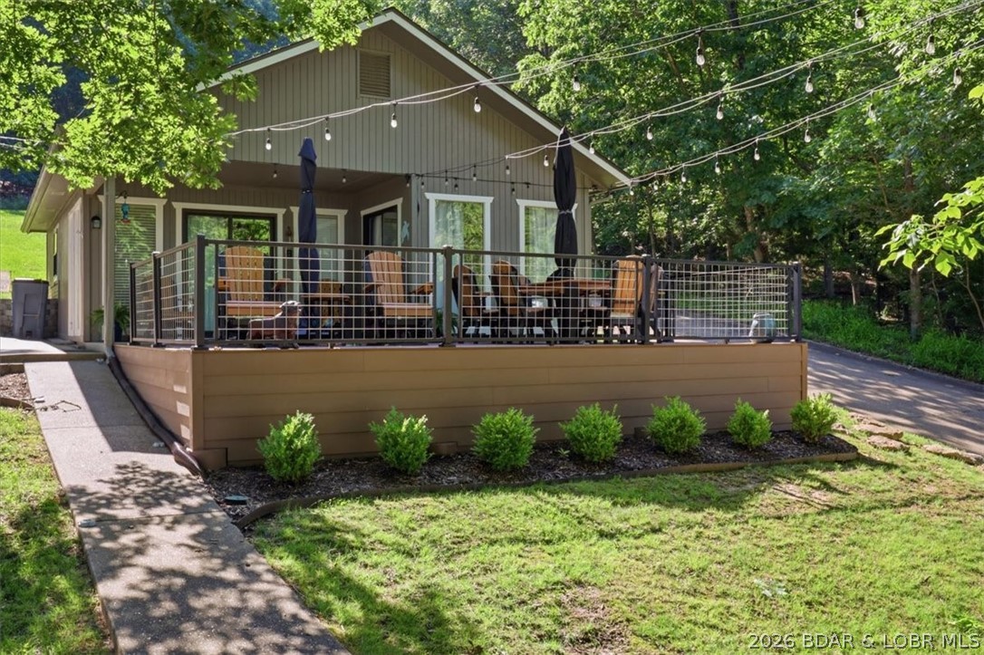 Lake days start here.

Tucked away in a peaceful setting with easy water access, this well-maintained 2 bedroom, 1 bath lake home is the kind of place people picture when they think about owning at Lake of the Ozarks cottage. From the vaulted ceilings and custom oak cabinetry to the inviting breakfast nook and covered patio, the home offers a warm, comfortable layout designed for relaxing weekends or full summer stays at the lake. This home might look small but it lives large with a welcoming covered patio and gentle yard for the kids and pets on a quiet street!
Additionally, you’ll find a spacious concrete driveway with ample off-road parking, a nicely kept yard, and a covered dock complete with a swim platform and boat hoist—making it easy to spend more time on the water and less time preparing for it. The nearby boat ramp adds even more convenience for lake days with family and friends. This home comes furnished so its move in ready! See attachments for full list of upgrades including new roof, new HVAC +new deck! Additional personal watercraft available separately with acceptable offer, including a 2008 Yamaha GP1300 jet ski and 2008 Yamaha VX110 jet ski, well maintained.