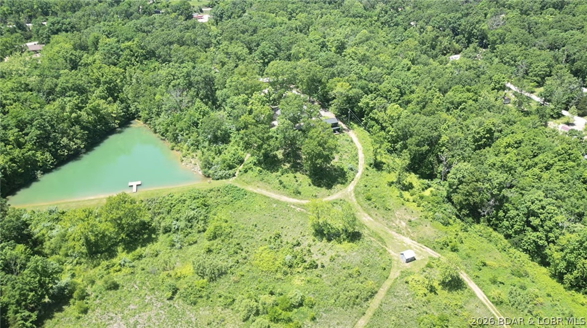 Discover a private slice of paradise just six miles from historic Bagnell Dam! This stunning 60-acre retreat offers total seclusion and quick lake access just off the four-lane. The land is a nature lover’s dream, featuring a spring-fed swimming pond stocked for fishing, a picturesque creek with a natural waterfall, and a private new fruit orchard. Explore your domain via a mile-long trail perfect for hiking or ATVs. The main home, fully remodeled in 2018, features oak hardwoods, high-end fixtures, and a 2018 HVAC/furnace. Recent 2025 upgrades include a new roof, gutters, well pump, and pressure tank. The brand-new guest house offers incredible versatility as a chic office/salon or secondary residence. Designed as a self-sufficient compound, the property boasts three wells—including an updated well house with 100-amp service—and ample room for a hobby farm. From the new composite decking on the dock to the efficiency of R32 and spray foam insulation, every detail is move-in ready. Experience unparalleled serenity and natural beauty in the heart of the Ozarks. Truly one-of-a-kind! VIDEO: https://www.youtube.com/watch?v=PaJ2S_DTWPM