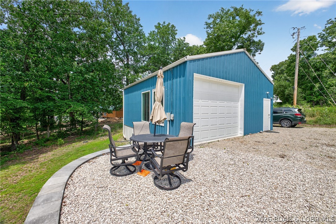 Lake life made simple! Newly built in 2024, this unique barndominium-style retreat offers low-maintenance living with deeded Lake of the Ozarks access, including a swim beach and boat ramp just a short walk away. Furnished open-concept interior features drywall walls, metal ceilings, a simple kitchen with Bosch dishwasher, full bath with walk-in shower, washer/dryer, concrete floors, and a 9'x14' insulated garage door for flexible use. Spray foam insulation, including beneath the concrete floor, helps provide year-round efficiency. Enjoy the convenience of a new septic system, private well with new pump, Navien on-demand propane water heater, water softener, and new gutters with snow guards. The property is RV-ready with full hookups including 20, 30, and 50 amp service, water, and septic. A retaining wall, surveyed lot, storage shed, seasonal lake view, and NO HOA make this an ideal weekend getaway, investment property, fisherman's retreat, or home base for all your Lake of the Ozarks adventures