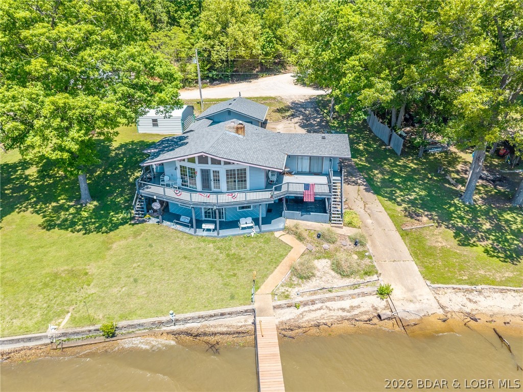 Nice, well maintained lake front home with fantastic main channel view on a double lot.   Vaulted ceilings in Great Room with wall-to-wall windows provide you with a beautiful view of the morning sunrise. Single level living on the main level.  Large master bedroom with sliding glass doors allows for access to the deck. Lower level has a second bedroom, bath and a spacious living area that provides plenty of room for a game room, sitting area, or additional sleeping arrangements as needed.  Newer windows, roof, flooring, kitchen cabinets and furnace.  Gentle slope lot allows for easy access to the dock and also provides an area for family and friends gathering. There is a detached three car garage with a covered walkway to house.  An additional 20 x 20, metal two car garage, gives you plenty of parking, storage and work space options. Washer and dryer hookups on the main level.  Lower level has a wet bar.