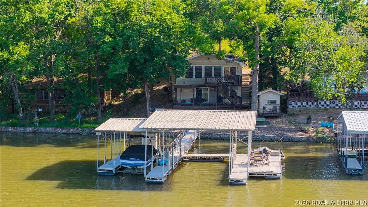 Lakefront living with a gentle walk to the water, deep water, and exceptional dock amenities await at this 2 bedroom, 2 bathroom home on the 3 mile marker of the Big Niangua arm. Located in a protected no-wake cove shared with Nautifish, this property offers the perfect balance of calm waters and convenient access to popular lake destinations. The cruiser dock includes a 16x40 slip, 10x24 slip, boat lift, and PWC lift, with most furniture and furnishings included. The exterior is designed for easy lake living with a rare, gentle lakefront lot, concrete stairs leading directly from the driveway to the dock, and a spacious two-level lakeside patio deck that's ideal for entertaining. Ample parking includes covered spaces for 3 vehicles, along with 2 additional storage sheds, a large crawlspace, and a customized "man cave" shed offering plenty of room for lake toys. The roof was replaced in 2012, and nightly rentals are allowed, providing flexibility for personal enjoyment or investment potential. Whether you're looking for a full-time residence, weekend retreat, or income-producing property, this home offers an outstanding combination of location, convenience, and lakefront lifestyle.