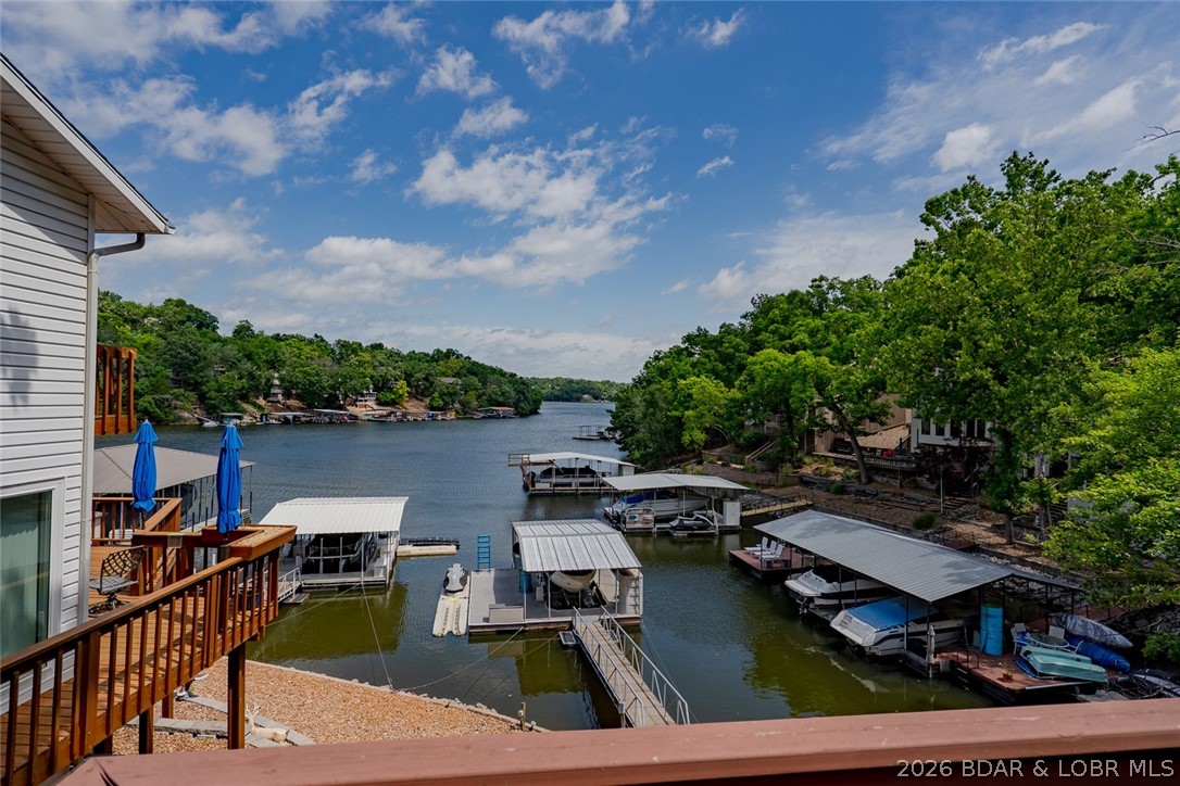 Lake living doesn't get much better than this! Nestled in a deep-water cove with stunning main channel views, this well-maintained waterfront home offers the perfect blend of comfort, convenience, and outdoor enjoyment. Blacktop roads lead directly to the property, featuring ample parking (community parking across the drive) central sewer and water, and attractive low-maintenance landscaping. Brand New Roof in 2026. Easy access to the waterfront includes gentle steps to the dock equipped with a boat hoist. Inside, the open-concept design showcases a spacious great room anchored by a beautiful stone wood-burning fireplace, flowing seamlessly into the kitchen and dining area. The main level also offers a bedroom, full bath, and laundry room with storage. Upstairs, you'll find two additional bedrooms, a full bath, and a primary suite with a walk-in closet. Home is being sold furnished. Relax or entertain on the expansive lakeside deck overlooking the water. HOA dues of only $125 a month help simplify ownership by covering water, sewer, road maintenance, and trash service. Excellent swimming, boating, and year-round lake fun await right outside your door!