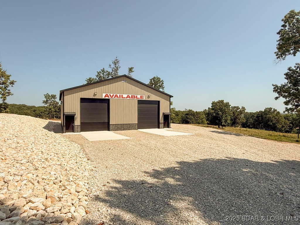 This newly constructed, multi-purpose shop is ideally located at the intersection of Highway 135 and Highway 5 in Laurie, Missouri. Sitting on a level lot, this 25’ x 60’ unit offers exceptional functionality with 16-foot ceilings and an oversized 12’ wide x 14’ tall garage door—perfect for accommodating large vehicles, equipment, or recreational toys. Built with quality in mind, the structure features 2x6 construction, textured drywall, full insulation, and 200-amp electrical service. Plumbing is roughed in and ready for a bathroom installation, with access to city sewer—providing flexibility for future upgrades. Designed for year-round use, the unit includes a 100-inch industrial ceiling fan and a 50,000 BTU forced-air gas furnace to ensure climate control in all seasons. There Is a RV Clean Out Located on the side of the Building. Whether you’re looking for a personal man cave, storage for vehicles or gear, a workshop, or a commercial-use space, this unit offers endless possibilities. Just 5 minutes from Ozarks International Raceway, this location is both convenient & highly desirable. The bathroom is roughed in & you have the option to add a Full Bathroom for a $5,000 add-on.