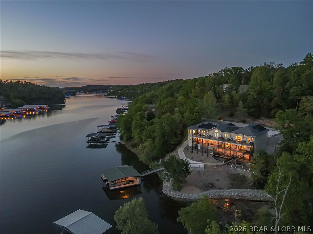 Amazing Rental Potential! Solar Efficient Lake Home with energy bill averaging $70 per month!You don't want to miss this exclusive lakefront home with dock in Linn Creek Cove, MM31, Lake of the Ozarks.This custom furnished home has a 2023 new build with a 2010 fully renovated wing located in the established quiet Cross Creek neighborhood, sitting on 1.74 acres, has a fabulous lakefront view with 621 ft of Lakefront! The home boasts 5670 sq. ft. of interior living space,4 car garage bays with oversized garage area,& add'l parking on the wide, gentle sloped concrete driveway.The main interior floor offers open floor living, vaulted ceiling,stacked stone gas fireplace, chef's kitchen & dining room with hardwood floors. It features a great room, 2 master ensuites, 2 add'l beds, add'l 1.5 baths, & laundry. Lower level boasts family rm, entertainment rm, 3 beds, exercise/bonus rm, office/bedrm, 3 baths, bar room, & dining area. Enjoy your hot tub, wet bar, sitting area, game area, & lakeside firepit. A concrete dock with 2 boat slips, double PWC slip, swim platform,dock bar, & storage area completes the package. A perfect home to enjoy year-round or seasonal with your family and friends!