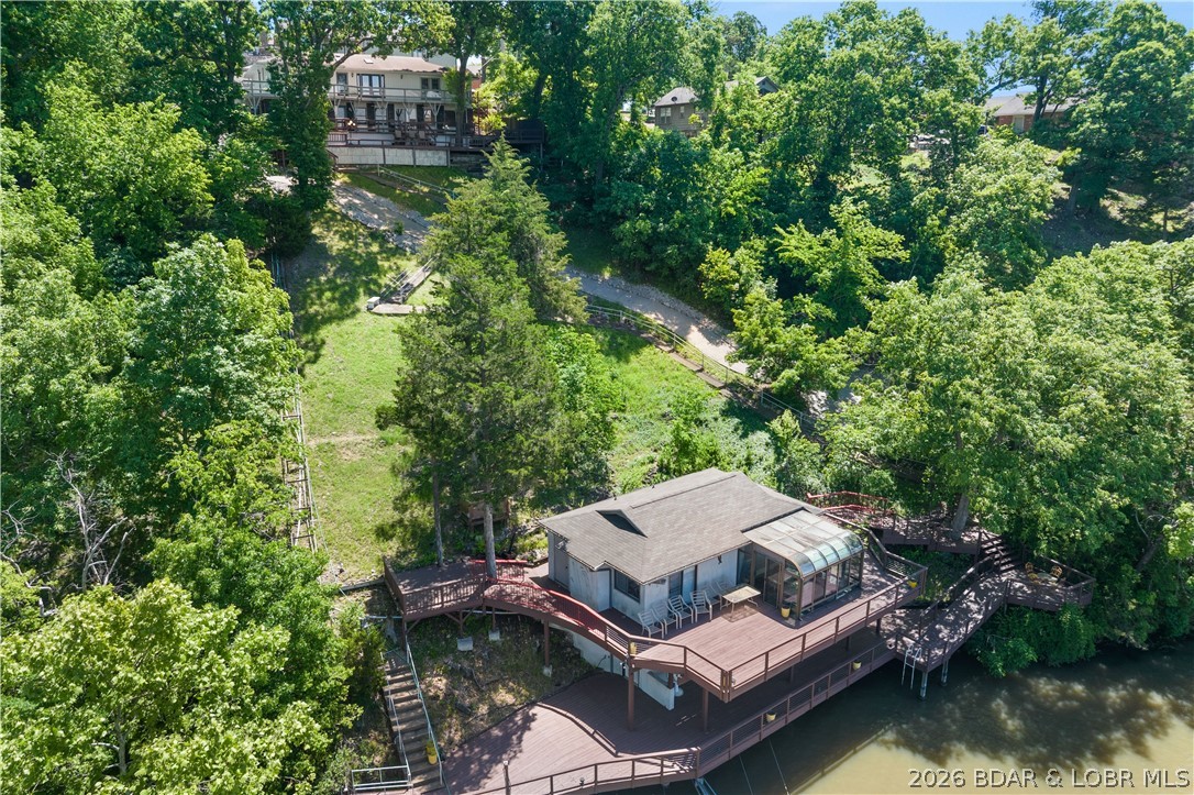 Don't miss this incredible lakefront opportunity featuring a 5BD/4BA main home plus a 1BD/1BA guest house perched over the water on MM 17 in Lake Ozark! Offering big water views, a prime location by land and water, and nightly rental approval, this property is ideal for full-time living, multigenerational use, or investment. The one-of-a-kind guest house offers a large lakeside sunroom, full kitchen, living room, spacious bedroom, full bath, and extensive wraparound decking. Enjoy a newer 2-well concrete dock (12x36 + PWC slip) with a swim platform and storage/bar room with electric. The main home features two full kitchens (including a newly remodeled main kitchen), two living areas, two primary suites, two dining spaces, and a 2-car garage. Additional highlights include two wood-burning fireplaces, indoor/outdoor speakers, abundant decking (recently repaired and resealed), vaulted ceilings, newer roof and stucco on the guest house, flat driveway, main level living, and approx. 30' of water depth. A new cart path to the dock adds easy access. Truly exceptional lakefront living—turn-key and ready to enjoy!