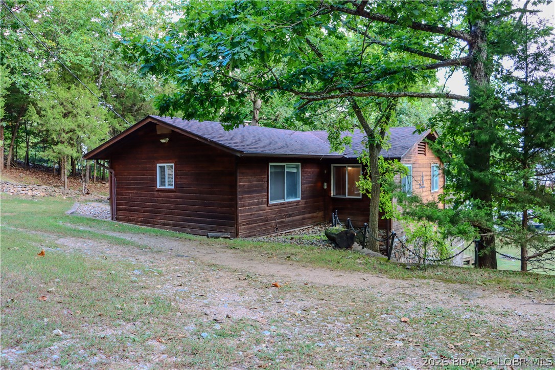 Welcome to your private lakefront oasis on the 2 Mile-Marker of the Gravois Arm! This charming 3-bedroom, 2-bathroom cabin has been cherished by the same family for generations and combines rustic warmth with modern updates! Step inside to find an inviting open floor plan with vaulted ceilings, Knotty Pine & a cozy wood-burning fireplace that creates a true cabin feel. The home has been freshly updated with new flooring, new water heater, HVAC system and a new roof, ensuring low maintenance living for years to come. The outdoor spaces are just as impressive as the interior. A huge deck overlooks the lake, providing a perfect spot for morning coffee or evening gatherings. Down below, a stone patio with built-in grill sets the stage for cookouts & entertaining. A 10x20 slip in the community dock is included and the dock has just been brought up to code and is in the process of being resurfaced!  Short-term rentals are allowed, giving you the option to enjoy the home when you choose and generate income when you’re away. Don’t miss your chance to own this one-of-a kind lakefront property that blends comfort, convenience, and endless recreation.