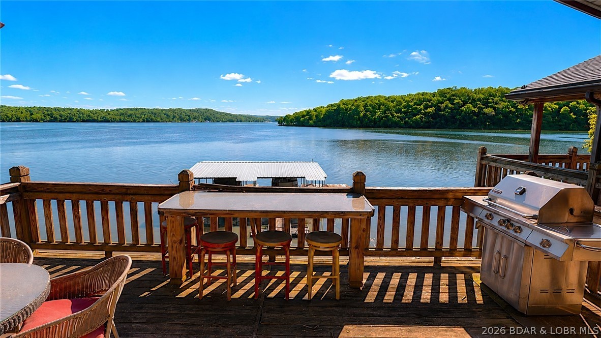 Originally a Quonset hut, this unique lakefront property blends distinctive character with modern comfort at the 74MM of the Osage. The original structure remains incorporated into the kitchen featuring custom cabinetry, countertops, Bosch appliances, gas cooktop & pot filler. Hardwood floors run throughout with beautiful lake views. This ranch-style home with 3 non comforming bedrooms & a walk-out basement includes a spacious bunk room, wet bar, laundry, and second bath. Above the boathouse is the 3rd bedroom connected by an expansive deck & additional storage for your lake toys. Outdoor spaces are designed for lake living with multiple covered & open decks, hot tub, martini deck, and a detached 2-car garage with loft connected by breezeway. The 2-well dock includes boat lifts & swim platform. Exterior features vinyl siding and mostly metal roofing, with some deferred maintenance is needed and is reflected in the price. This tranquil, one-of-a-kind property offers incredible potential, outstanding value, and is being sold mostly furnished and as-is.  Come view to see this true value! Your lake life is awaiting!