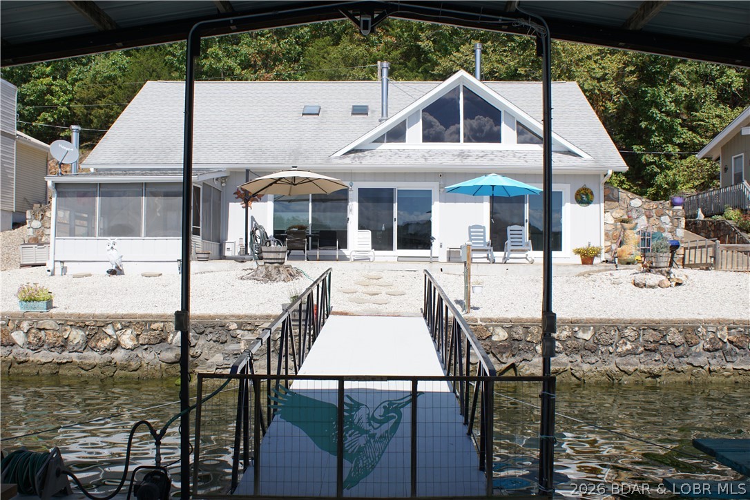 List price is below appraisal, NEW ROOF COMING SOON! Sitting at the 3.5 MM in a large quiet cove right off the Gravois arm, this wonderful home sets the stage with the gorgeous views. The 79 feet of lakefront has a beautiful stone seawall, steps for swimming, LEVEL LOT WITH DEEP WATER, & a dock that has state-of-the-art Marine Fiberglass flooring, (preferred over concrete), & by special design, a wake control feature that reduces movement & saves wear and tear on the Dock. Both of the two slips can be enlarged to a 12X30, the there is a PWC slip with a covered swim platform, and plenty of room for family entertainment. Large patio that has panoramic views, gorgeous sunsets & stretches from the screened in porch to the other side of the house. The 3 large patio doors that look over the deck are Passive Solar Technology, helps warm your home in the winter, and cool it in the summer! The main living area has an updated kitchen, open floorplan, dining area, and a living area with views of the lake as well as a lakeside master bedroom with a private screened in porch. 2 Woodstoves on both levels, upper level has two bedrooms, and a storage area or a bedroom/craft room.