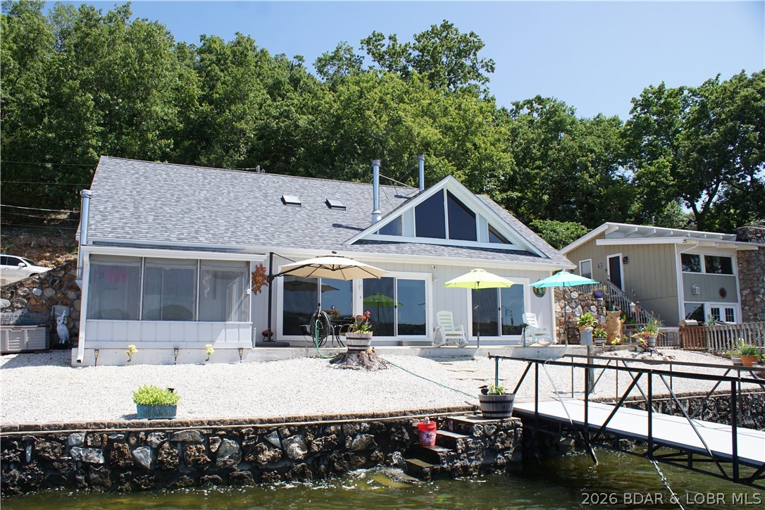 NEW PRICE, Below Appraisal, and Brand New Roof 7/16/2026. Sitting at the 3.5 MM in a large quiet cove right off the Gravois arm, this wonderful home sets the stage with the gorgeous views. The 79 feet of lakefront has a beautiful stone seawall, steps for swimming, LEVEL LOT WITH DEEP WATER, & a dock that has state-of-the-art Marine Fiberglass flooring, (preferred over concrete), & by special design, a wake control feature that reduces movement & saves wear and tear on the Dock. Both of the two slips can be enlarged to a 12X30, the there is a PWC slip with a covered swim platform, and plenty of room for family entertainment. Large patio that has panoramic views, gorgeous sunsets & stretches from the screened in porch to the other side of the house. The 3 large patio doors that look over the deck are Passive Solar Technology, helps warm your home in the winter, and cool it in the summer! The main living area has an updated kitchen, open floorplan, dining area, and a living area with views of the lake as well as a lakeside master bedroom with a private screened in porch. 2 Woodstoves on both levels, upper level has two bedrooms, and a storage area or a bedroom/craft room.