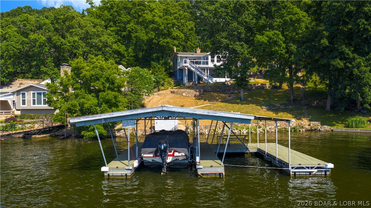 287 Shoe Lace Drive in Camdenton brings Lake of the Ozarks living to life with 140 feet of shoreline and spectacular lake views that steal the show from sunrise to sunset. This updated 3-bedroom, 2-bath retreat offers comfortable one-level living with bright, welcoming spaces, LVP flooring, Cambria Quartz countertops, refreshed cabinetry, newer appliances, updated windows, a walk-in shower, and a cozy woodburning fireplace. Step outside and choose your favorite place to unwind among the covered and open decks, patio, porch, and lakeside gathering areas made for morning coffee, sunset dinners, and memorable weekends with family and friends. The 2-well covered dock features 10x30 and 10x20 slips, a boat hoist, electric, updated decking, and an ice breaker. Rentals are allowed, creating possibilities for a personal lake escape, vacation rental, or investment property. A walkout storage basement, carport, shared well, and new engineered septic installed in June 2026 complete this inviting lakefront package.