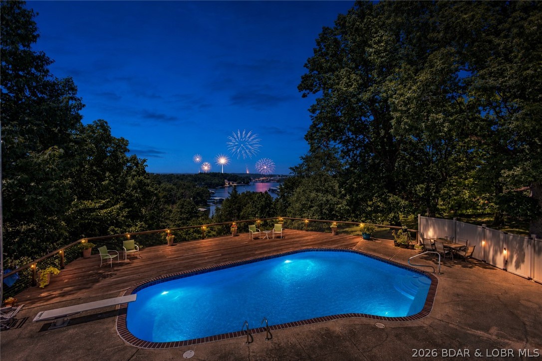 Nestled on over 2 acres with panoramic views of Lake of the Ozarks, this unique & charming property checks all the boxes for lake living! Perfect for entertaining, boasting 5 bedrooms & 4 well-appointed bathrooms, with the primary suite having a private deck & office.  At its heart lies a large resort-style pool, spacious decks, all designed for hosting large gatherings, excellent for relaxation & celebration. Expansive windows throughout frame breathtaking lake vistas & capture the vibrant sunsets. Inside, the recently remodeled interior showcases a new kitchen, featuring cabinets, quartz, a high-end induction cooktop, & LVP flooring, complemented by updated lighting, & 3 new fireplaces. The walk-out lower level offers endless possibilities including a rec room, media area, multigenerational living or potential rental income. Recent enhancements include new windows, roof, refreshed decks, flooring, EV charger, & enhanced pool features. With the allure of lake views, lake access, & available boat slips at Alhonna Resort, this property is a stand out as a premier residence, a vacation retreat, or a promising investment opportunity with no HOA fees & the option for short-term rentals