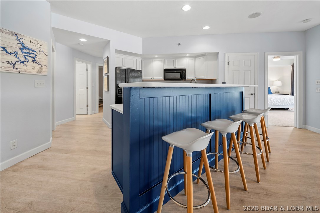 Beautifully renovated from top to bottom, this turnkey condo features high-end finishes and a fresh, modern style throughout. The sellers remodeled with long-term comfort and quality in mind, investing in thoughtful upgrades and timeless design. Spanning two spacious levels, the home offers 4 bedrooms, 3 full baths, and two separate living areas—perfect for hosting guests or relaxing in comfort. The updated kitchen showcases quartz countertops, a classic white subway tile backsplash, and a new range. Fresh paint throughout and new luxury vinyl plank flooring on both levels give the home a clean, cohesive feel. Major systems have also been updated, including HVAC, furnace, and water heater, providing added peace of mind. The lower-level family room features a wet bar with beverage fridge and access to the lakeside deck. A lower-level bedroom includes an ensuite bath, ideal for guests, while also accessible from the main living area. Enjoy lake views from the screened upper deck or the open deck below. Located in the gated Lighthouse Pointe community with elevator access, excellent storage, guest parking, and boat and PWC slips just steps away.