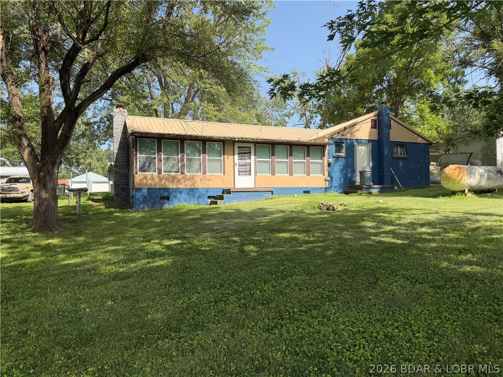 Rare 4-Lot Lakefront Property;Bonus Dock Lot  Embrace this lifestyle with this multi-lot property in Lazy Acres! Situated at the 69MM, this unique offering includes 4  lots, providing a gentle rolling waterfront yard with seamless water access & boundless room to entertain, play & splash away. The charming home radiates vintage lake warmth, featuring beautiful wood paneling, low-maintenance finishes, cozy wood-burning fireplace, & inviting open-concept kitchen/dining/living area. Officially a 1-bedroom 1-bath home, the lakeside sunroom features windows on two sides—offering panoramic views & the perfect footprint for a high-capacity bunkhouse. Enjoy a 2-car attached garage equipped with a second bathroom—perfect for rinsing off after a day on the lake. The yard with seawall is ready for your custom dock build, having a bonus garage/storage building right by the water's edge—a great place for parties. A few lots away, this purchase includes a bonus 2nd lakefront lot complete with a private dock & deep-water access! Whether you are looking for the perfect weekend retreat or a year-round escape, this gem is a must-see. Come take a look! BEING SOLD 'AS IS'