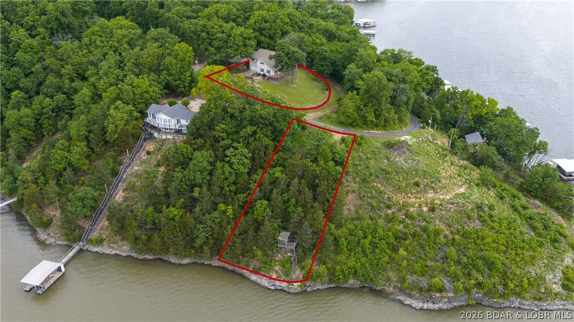 Lakefront living at its best! Check out that View! This beautifully maintained 3-bedroom, 3-bath home in Rocky Mount offers  2,600 square feet and feels more like a full-time residence than just a weekend getaway. Perfect as either a primary home or vacation retreat, the open main level features a spacious family room with a fireplace, a large dining area, a well-appointed kitchen with island, and a full bath. Take in panoramic lake views from the screened-in porch or the expansive wraparound deck, ideal for entertaining or relaxing. Upstairs, the oversized primary suite showcases breathtaking lake views, a luxurious ensuite bath, and a walk-in closet, while two additional bedrooms and another full bath complete the upper level. The unfinished basement and attached two-car garage provide excellent storage and future potential. There is a Martini Deck already in place, and With 92 feet of waterfront this property is ready for you to enjoy the best of Lake of the Ozarks living at the 5MM, just minutes from waterfront restaurants, gas docks, and local attractions. With this Private setting, unforgettable views, endless memories await!