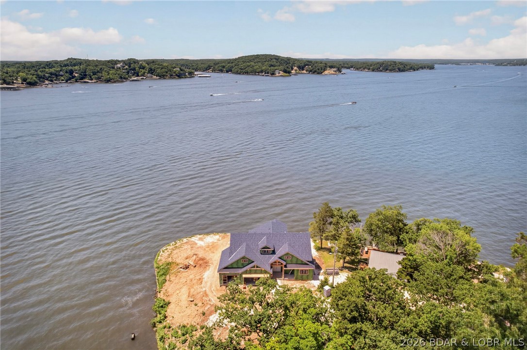 Brand new lakefront point estate showcasing breathtaking panoramic views from 2 combined lots with 316 feet of gentle shoreline, at the 4 Mile Marker of Lake of the Ozarks.  Designed for luxury living and effortless entertaining, this exceptional residence offers an unparalleled waterfront lifestyle with high-end finishes and thoughtfully curated throughout.  The stunning lakeside pool overlooks expansive main channel views, creating a private resort-style setting.  Inside, guests will enjoy a media/theater room, spacious game room, custom wet bar, private swimming pool just one step off the lower deck and multiple gathering spaces designed for memorable entertaining.  Sophisticated architecture, premium craftsmanship and extraordinary lake views combine to create a one-of-a-kind retreat that rivals a five-star resort.  Whether hosting family and friends, or enjoying a private lakeside escape, this remarkable new construction home delivers the ultimate luxury in waterfront living.  Perfect set up for huge custom designed dock with a protected breakwater system.