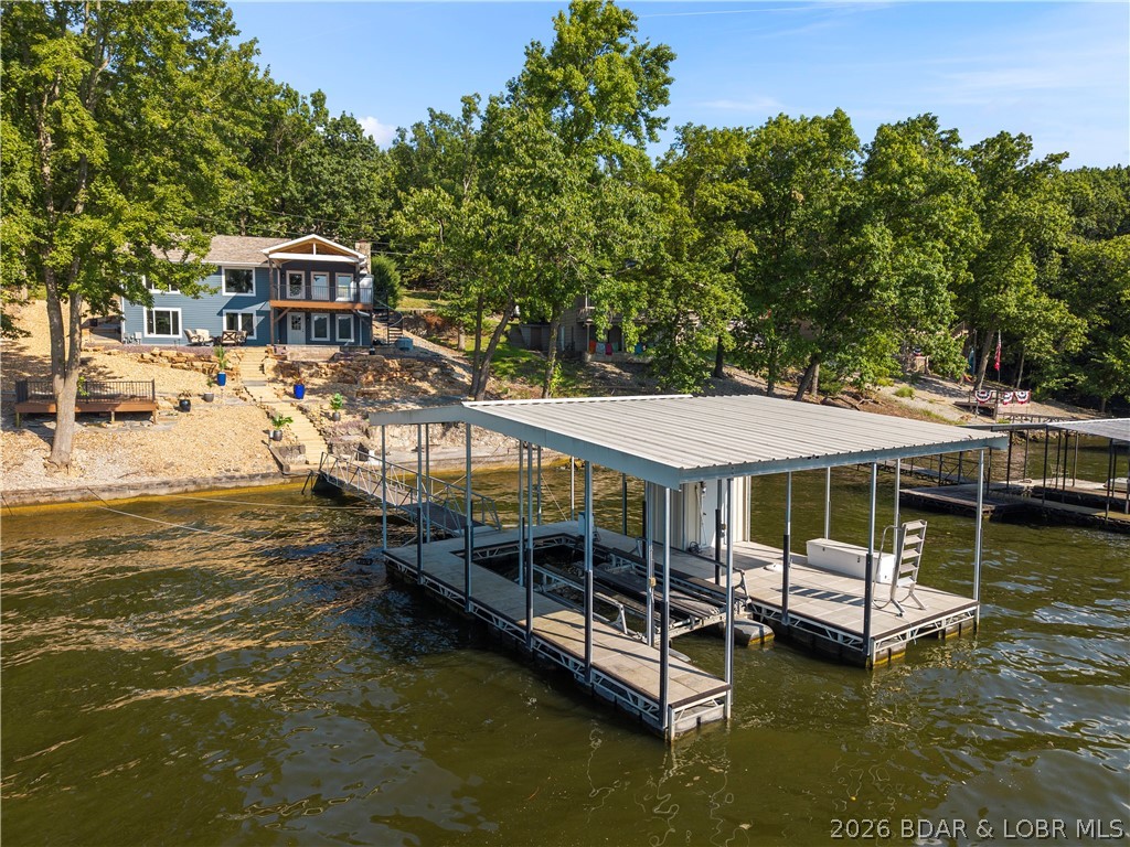 Lake life doesn't get much better than this!! Completely move-in ready & packed with updates, this waterfront retreat lets you skip the projects & start making memories from day one. Offering BIG main channel views, gentle topography to the water, nice driveway, & layout designed for making memories. Inside is bright, inviting interior featuring LVP flooring, quartz kitchen tops, refreshed cabinetry & updated bathroom vanities & showers. Spacious floor plan offers 4 beds/4 baths, 2 wood-burn fireplaces & walkout lower level complete with second family room, wet bar/kitchenette & large bunk bed rooms. Outside is where lake living takes center stage. Relax on huge covered deck, sip your fave drinks martini deck at waters edge, make room for new hot tub, gather around lakeside fire pit, or take advantage of concrete dock with 12x32 slip equipped with Polylift hoist & First Mate remote with 89' of lakefront to expand. Conveniently located by both land & water, you're just minutes from Margaritaville, golf, shopping, dining, & Paradise Restaurant just a quick boat ride away. Whether you're searching for a full-time residence or rental investment- this is one to take look at!