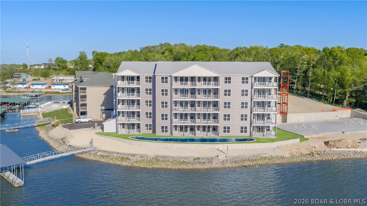 Discover the pinnacle of Lake of the Ozarks living at Niangua Commons, the newest premier address situated at the 3-mile marker of the Big Niangua. Just past “Four Corners,” this development stands out with a rare, level landscape that places you directly at the water’s edge—no steep hills or grueling stairs. These sophisticated 3-bed, 2.5-bath condos offer 1,515 sq. ft. of open-concept design, featuring upscale finishes and massive windows that frame panoramic lake views. The primary lakeside suite provides a true retreat with double vanities and a custom walk-in shower. Life here is defined by effortless convenience, from elevator access to a lakeside pool with on-site restrooms. Boaters will appreciate slips available up to 14x40, along with PWC slips featuring drive-on lifts. Located minutes from iconic hotspots like The Cave Bar & Grill and Nautifish Rum Bar, you are perfectly positioned for both high-energy entertainment and quiet relaxation. Whether you seek a full-time residence or a turn-key getaway—with furniture packages available—Niangua Commons delivers an unmatched lifestyle. Don’t miss your chance to own the lake’s most accessible luxury.
