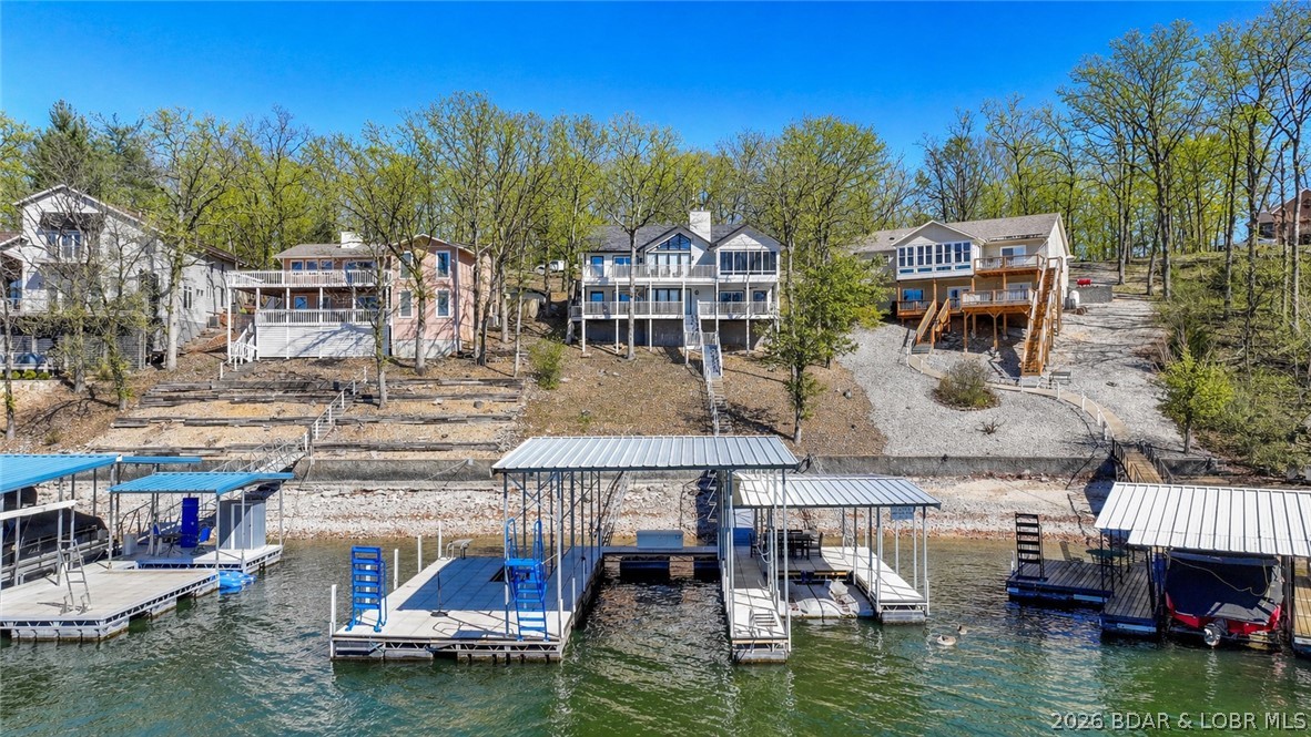 Big lake views, 5 bedrooms, over 3,100 square feet, and $170,000 already invested in upgrades—this Four Seasons lakefront home delivers a combination that is getting harder and harder to find in this price range. Perfectly positioned on a wide channel with easy access to the main lake, this home was designed for gathering, entertaining, and making the most of lake life. A climate-controlled sunporch and two expansive lakefront decks provide year-round spaces to relax, while the concrete cruiser dock is built for serious boating. Inside, nearly every major improvement has already been done for you including custom bunk additions, beautifully renovated and enlarged bathrooms with added en suite, quartz countertops, updated flooring, new lighting and hardware, fresh interior paint, wet bar, added walk-in closet, new water heater, and extensive dock work. The generous layout offers multiple living areas & sleeping spaces ideal for large families or hosting guests. Move-in ready lakefront homes with this much finished space, this level of updating, and this sought-after Four Seasons location are not easy to replace—buyers looking for value need to take notice. Close to popular hotspots!