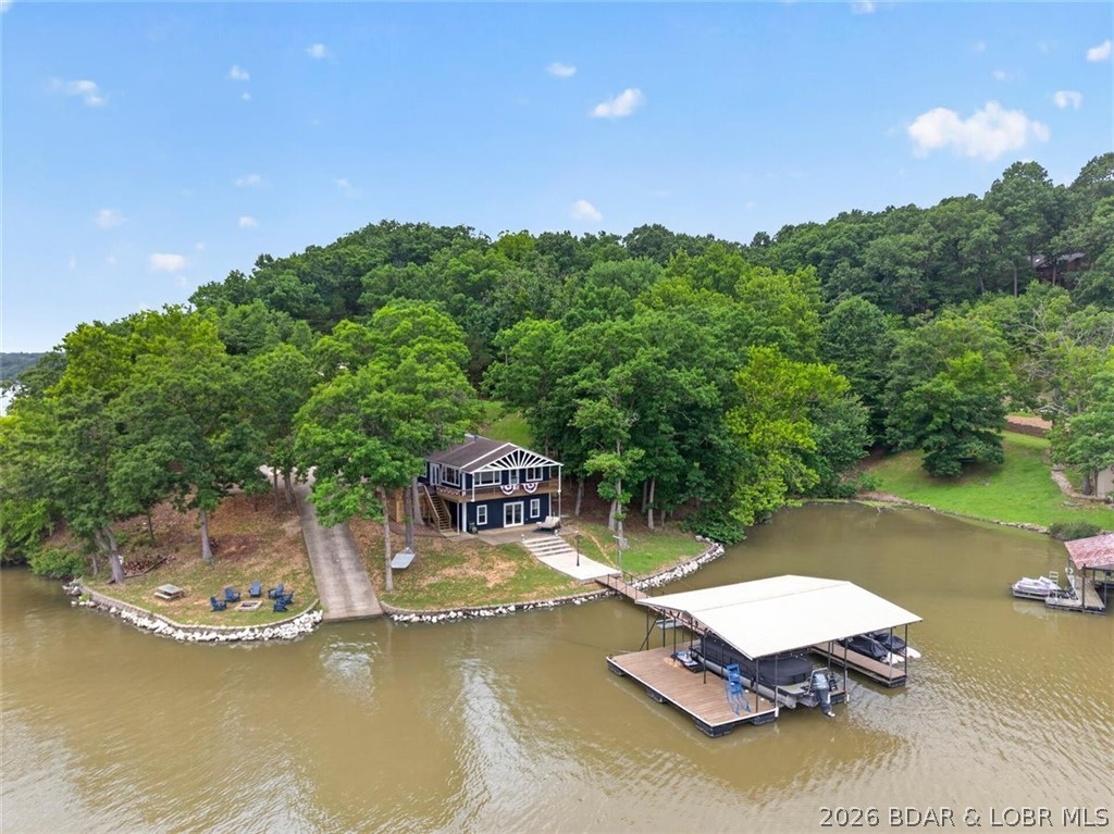 TURNKEY & MOVE IN READY!!! Packed with features that are hard to come by! Situated on four lots with 230 feet of shoreline at the 62MM, this 4-bedroom, 3-bath home pairs a gorgeous main channel view with cove protection, a private boat ramp, and an easy walk to the dock. Long list of updates including exterior/interior paint, flooring, fixtures, stainless steel appliances, bathrooms and more! The open-concept layout is perfect for gathering and the lower-level flex space offers room for a second living room and bunk space. Outside is a game changer for lake life with a spacious upper deck, large lakeside patio, fire pit near the water, expansive yard, and only a few steps to the two-well dock with a large swim platform. Room to build a garage, guest home, or simply enjoy the extra space! Whether you're searching for a full-time lake retreat, weekend getaway, or investment opportunity for nightly rentals, this property checks every box. Located near The Wet Spot, Patriot's Point, Holliday Hills, and nearby gas docks, you'll enjoy calmer waters perfect for swimming, fishing, paddleboarding, tubing, and making lifelong lake memories.