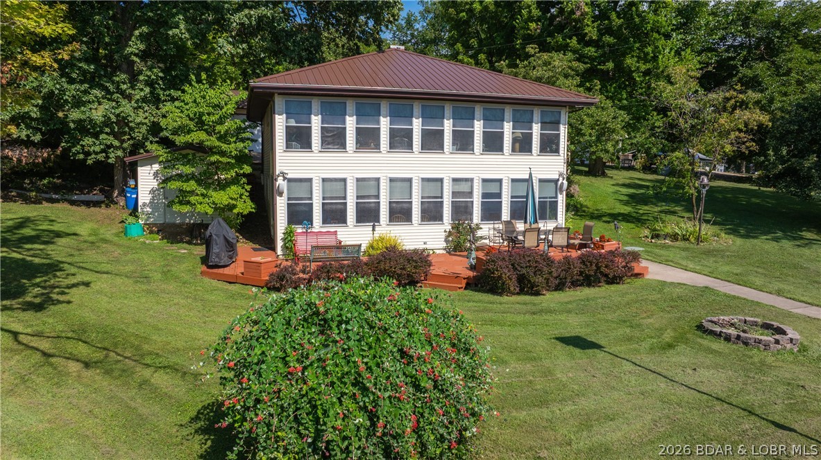 Discover this stunning, flat lakefront property with no HOA, offering seamless access from your patio to the water, plus a THREE car oversized garage.  This 3-bedroom, 2-bath home is designed for entertaining, featuring a spacious main-level family room, a 10x32 sunroom, and a large lower-level living area. Walls of windows on both levels frame breathtaking sunrise and sunset views year-round.  The property is perfectly set up for lake living, a boasting two well dock, a firepit area, and extensive storage, including a 15x15 golf cart shed and a dedicated shed for water toys. The garden area is ready to be revived, and the home includes significant recent updates: a newer heat pump, septic system, concrete driveway, and electric fireplace, with a brand-new metal roof scheduled for 2025. Car enthusiasts and hobbyists will love the heated 26x40 three-car garage, complete with a workshop area. Experience true lakefront convenience with flat, easy entry to your own private oasis.