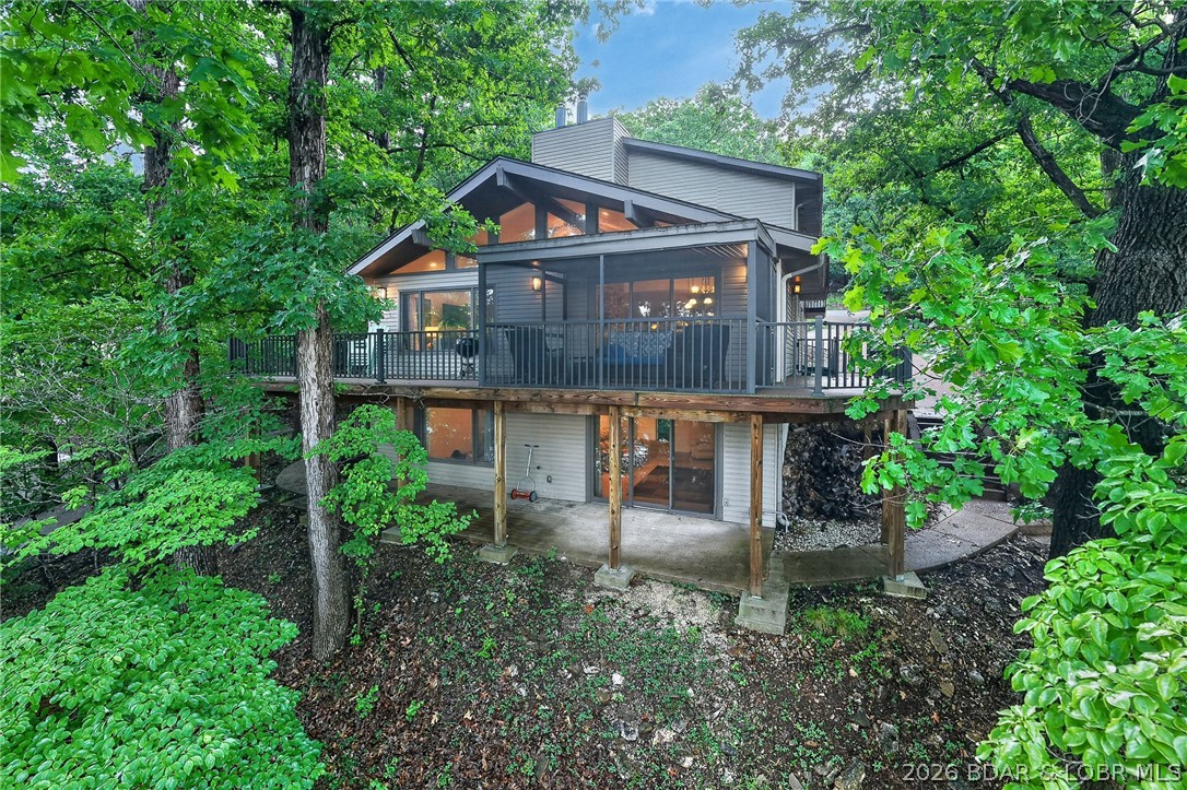Experience the best of Lake of the Ozarks living in this impressive Horseshoe Bend waterfront retreat! Perfectly positioned at the 4MM in a desirable cove location with main channel views & deep water! This 5 bedroom (two are ensuite), 4.5 bath home offers over 4,184 sq ft of thoughtfully designed living space, Vaulted ceilings, multiple gathering areas w/3 living rooms, charming stone fireplace w/wood stove insert on main level, Lower level fireplace w/pellet stove insert, beautiful kitchen w/plenty of cabinet space, large walkin pantry, 2 dining areas, office, screened deck off of main living area w/trex decking, open deck area, sunroom and covered patio create the ideal setting for relaxing or entertaining after a day on the water. With 95 ft of lakefront, private dock, detached 2-car garage, great parking and strong vacation rental potential, this property checks every box for the ultimate lakefront lifestyle. Located in a GREAT Cove close to Dock Knockers! Just Hop on your boat and enjoy!  Plus… if you don’t feel like taking steps to dock, there is a shared driveway with the neighbor that you can drive down to the lakefront .. perfect for a golf cart.