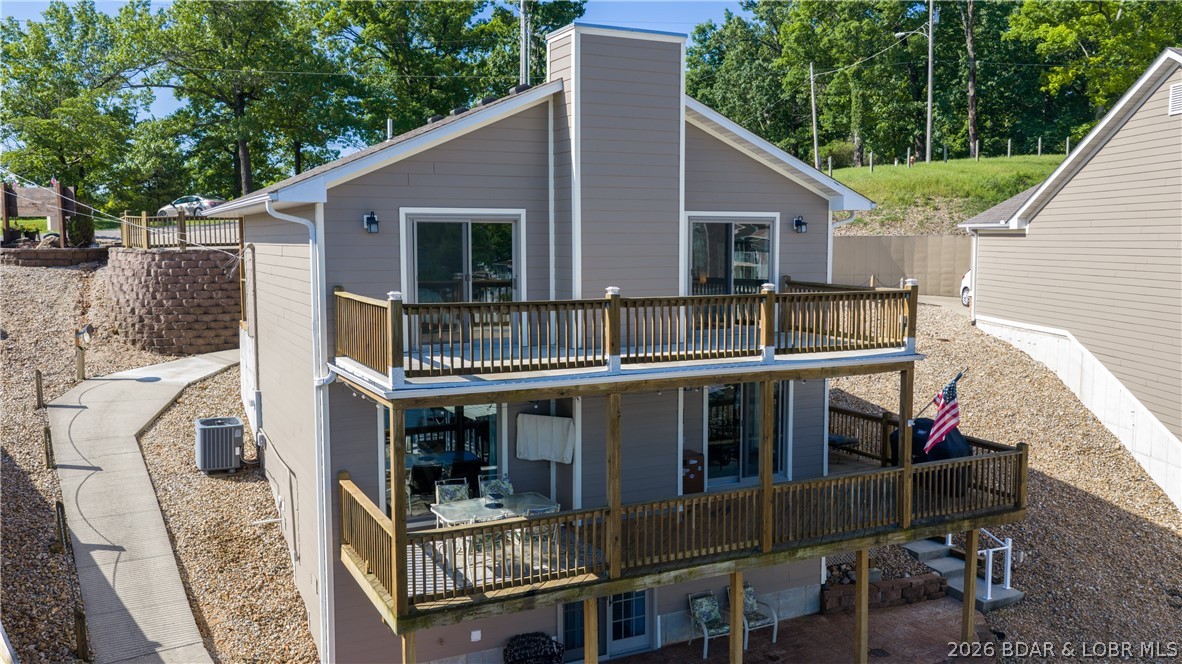 Have fun all year round at this beautiful furnished lakefront home with awesome main channel views! You're within walking distance to the Bagnell Dam Strip! So, you and your guests can go by boat, golf cart or car. Host your offshore race party with a front row view from your decks or the pool! It's a perfect home for entertaining. Watch the boats go by and even catch some sailboats! This 3 Bed/4 Bath is the only standalone home in Harbor One Condominiums with a 14 x 40 boat slip, a beautiful pool, a PWC slip and a golf cart path. Each bedroom has a balcony or patio and a view of the main channel. Primary ensuite has a dual vanity, a walk-in closet, an additional closet and a maintenance free deck with TUFTEK. Open concept Kitchen allows hosting your guests while being right there for all the fun on the partially covered deck. Lower level is a bonus room; could easily be a 3rd Bedroom in the Basement having a Kitchenette, Full Bathroom, laundry hookup, and a private patio with room to park the golf cart. Private stairs going to the lake! It's time to grab this one before it's gone! New roof and exterior paint 2024; new interior paint, fridge and exterior stairs 2026. Move in Ready!
