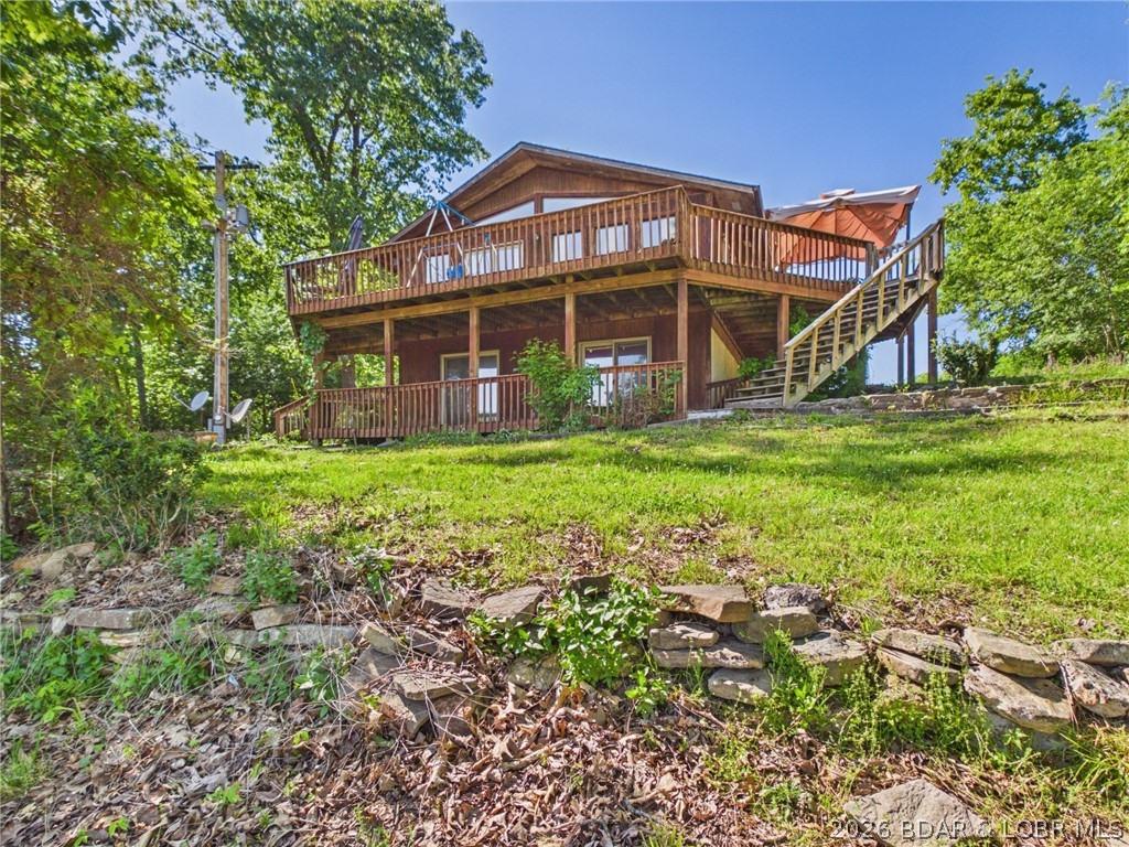 Stunning lake views and immense value await at this 5-bed, 2-bath retreat on nearly an acre. Overlooking the 8MM of the Little Niangua arm, this cedar-sided home is a prime "fixer-upper" opportunity on the Quiet Side of Lake of the Ozarks. The upper level features 2 bedrooms, a full bath, and an expansive open-concept living, dining, and kitchen area with oak cabinetry and a work island. Step outside to a massive 360-degree wraparound deck perfect for soaking in the lake views and scenery.
The walkout lower level adds 2 large bedrooms that open to the lower deck, a bathroom, laundry/utility room, and a 5th non-conforming bedroom. Bonus features include an Additional Dwelling Unit attached to the 2+ car garage/shop, complete with a private kitchen and bath and multi-use space. Newer 3-phase power at the shop is ready for your small business or hobby needs. While the home requires some TLC, it provides a solid foundation for your lakefront dream near premier fishing spots. With this rare combination of space, views, and potential, it is time to make the Lake of the Ozarks your permanent destination!