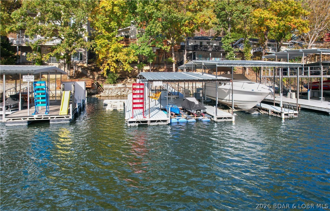 Looking for a 2-bedroom home in Lake Ozark sitting directly on the lake but at a reasonable price? This furnished getaway on 8 Walnut Ct offers 40 feet of deep water shoreline in a quiet no-wake cove on Lake of the Ozarks. Whether you're searching for a cozy weekend retreat or an income-producing vacation rental, this one checks the boxes. Inside, the home welcomes you with vaulted ceilings and abundant natural light thanks to transom windows above the lakeside sliding doors. With just over 1,000 square feet, it offers 2 bedrooms, 1.5 bathrooms, and a comfortable open living space. The lakeside deck is the perfect spot to take in all the sights and sounds of the water. The sale includes furnishings, appliances, a private dock, boat hoist and two pwc hoists—everything you need to enjoy lake life right away. The lake location is ideal with a calm swimming and great fishing spot. it’s ideal for investors or buyers seeking a turn-key second home. Imagine mornings on the deck, afternoons on the boat, and evenings by the water—all from your own piece of Lake of the Ozarks.