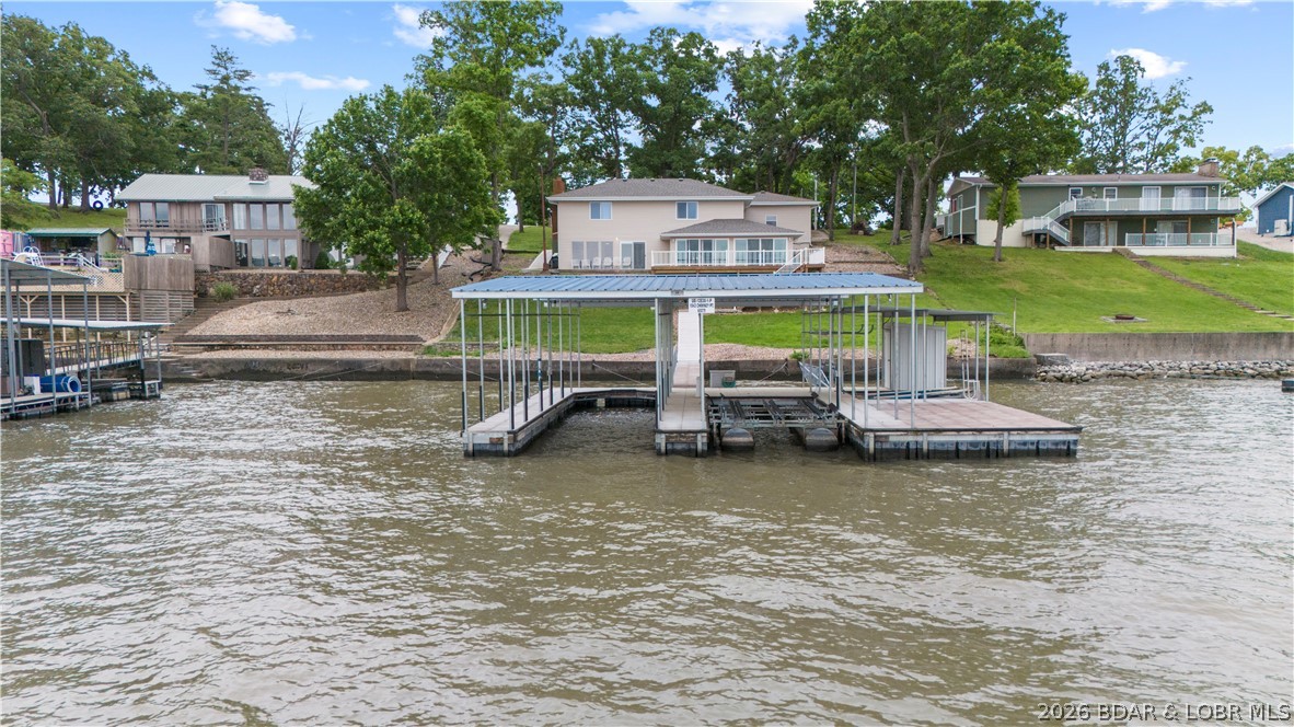 Experience unparalleled lakefront living where every detail enhances your connection to the water. This stunning 3-bed, 2.5 bath home offers breathtaking panoramic lake views from every angle. The spacious inviting interior features a sophisticated open concept, a cozy fireplace and a separate wet bar, ensuring drinks are always at hand. Enjoy the dedicated four-seasons room for bright year-round picturesque beauty. Retreat to the luxurious primary ensuite offering a haven of comfort and space with a walk-in shower and "his & hers" closets providing ample storage. Outside, a massive open deck stretches out offering generous space for al fresco dining or soaking in the beauty, dusk to dawn. A moderate slope leads to your private 3-well dock, including an 11 x 40 ft slip, storage shed for all your lake gear, and the convenient golf cart path ensures effortless access to the water. This exceptional 100 feet of prime lakefront property is completed by a 2-car garage offering ample space for vehicles, a golf cart, and extra storage. Don't miss your extraordinary chance to own this slice of paradise, where luxury meets leisure and every day promises a vacation.