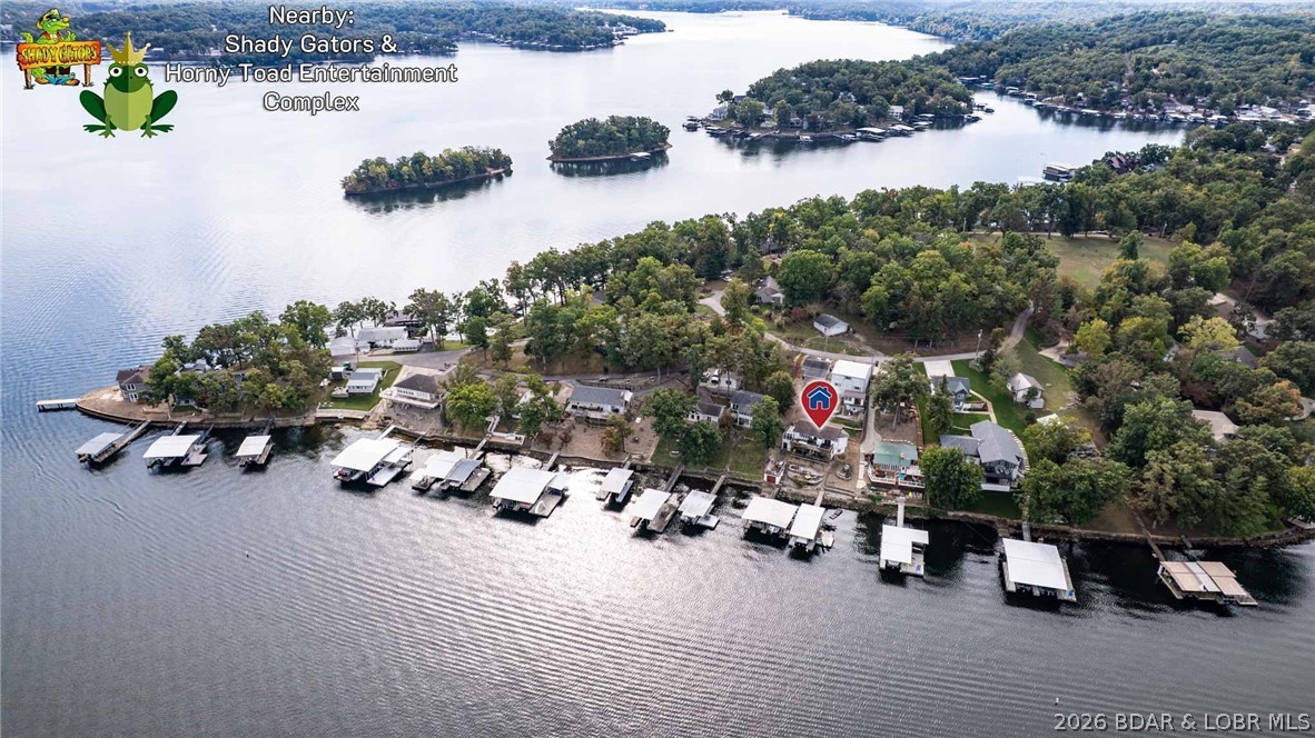 Now includes 10x35 Concrete dock and seller will consider ALL trades including small waterfront Condos, cars, boats, or RVs, toward purchase price. Terms and values subject to seller approval and lender guidelines. Move right in and bring all your lake toys! This 3-bedroom (plus potential 4th), 2-bath lakefront home is the perfect canvas for your Lake of the Ozarks dream retreat. Nestled on a gentle lakefront lot with cove protection and breathtaking main channel views, you’ll enjoy the best of both worlds from your private 2-well dock directly across from Shady Gators and Toad Cove at the 7MM. The home features a spacious lower-level living area with lake views from every window—ideal for entertaining or relaxing by the water. With its prime central location, this property offers incredible potential as a high-demand short-term rental or future development opportunity. A massive shop adds even more value, featuring a 12’ RV door, 8’ 2-car door, and ample workspace. Above the shop, a large loft with stunning lake views is ready to be finished into a guest suite or entertainment area. Huge closets, two tornado shelters, and endless options await!