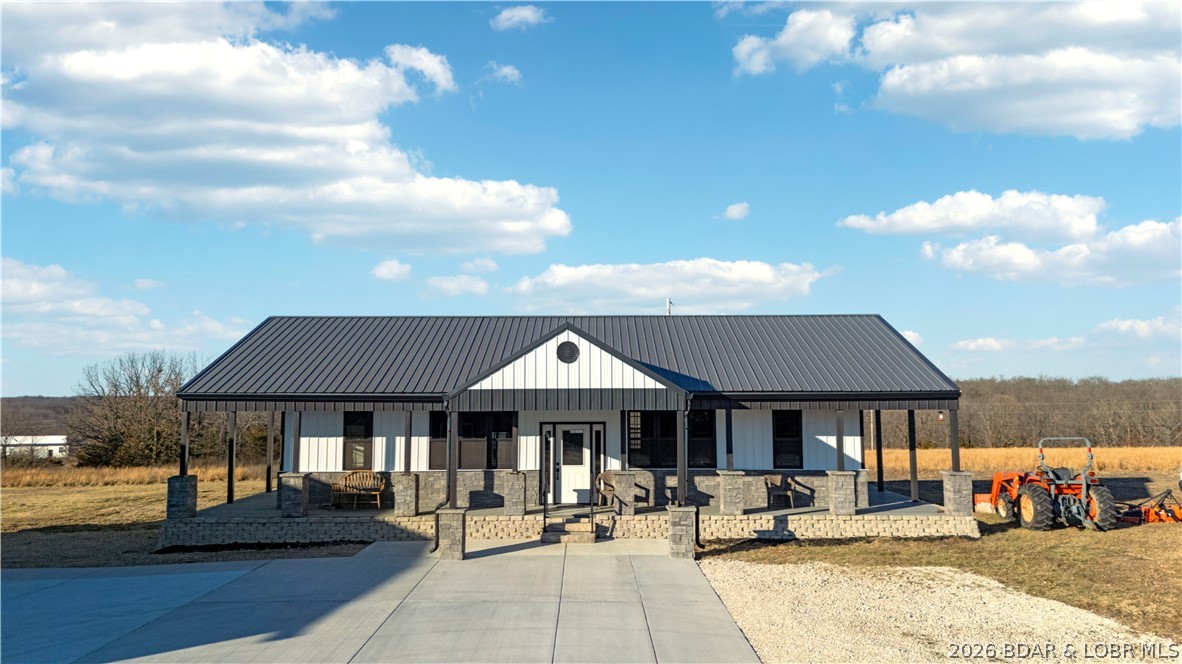 455 Camping Paradise Drive in Roach, MO brings together peaceful country living, usable acreage, and convenient access to Lake of the Ozarks. Set on 21.2 acres, this 2024 one-level home features 2 bedrooms, 1.5 bathrooms, a bright open layout, metal roof, and efficient ductless mini-split heating and cooling. The kitchen flows easily into the living and dining areas, creating a comfortable space to gather after a day outdoors. A detached 3-car garage/shop with a roughed-in half bath adds room for projects, storage, or future plans. The barn includes two separate fenced lots, ideal for animals, equipment, or hobby use. With open and wooded ground, level areas, scenic views, private well and septic, rentals allowed, and easy access to Camdenton, Hwy 54, and lake amenities, this property offers space to live, work, and enjoy the outdoors.