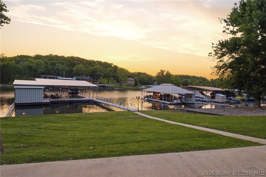 Lake life doesn't get much better than this! Nestled in one of the most coveted and peaceful no-wake coves in the lake, at mile marker 13, this fully furnished 4-bedroom, 2-bath waterfront retreat is ready for you to start making memories!  
Spend your days fishing from your private dock, cruising the lake, maybe buzz over to Lake House 13 to grab a bite, or Point Oasis to fill your tank. Imagine evenings relaxing at the dockside bar while enjoying the tranquil water views. The impressive 1 year old, 50' x 44' concrete dock was custom built! It features two boat wells (14x40 and 12x30), a swim platform, and a fish cleaning station, making it the perfect setup for boating and outdoor enthusiasts. Recent updates including a newer HVAC system, new roof, new siding. Additional parking pads provide for ample parking, which is hard to find at the lake. The detached two-car garage and RV hookup offer plenty of space for guests and recreational vehicles. Whether you're searching for a full-time residence, weekend getaway, or vacation rental opportunity, this turnkey waterfront property is a rare find. Schedule your private showing today and start living the lake dream!